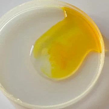 Close-up of translucent yellow gel swirled in a round white container