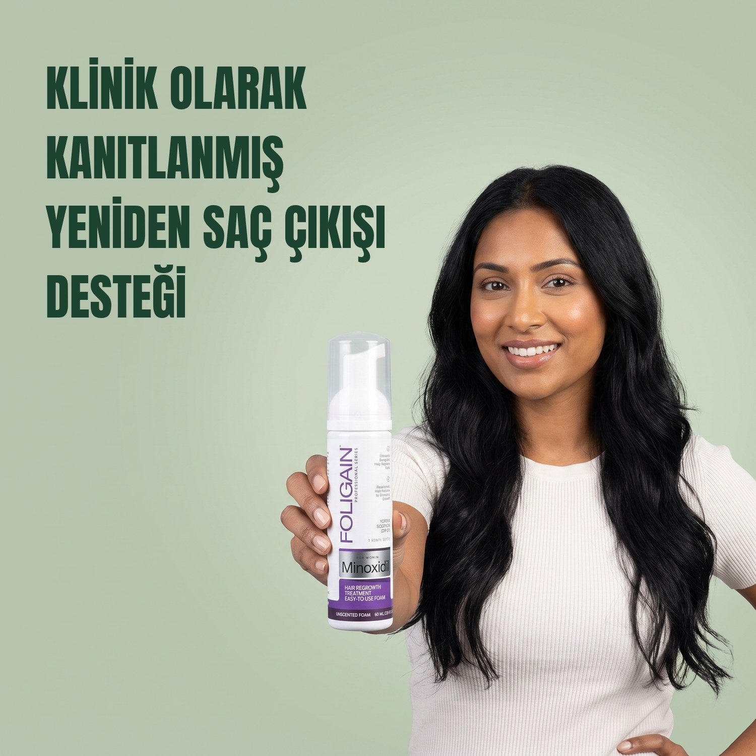 Yeşil arka planda elinde kadınlar için Foligain Minoksidil %2 köpük tutan kadın
