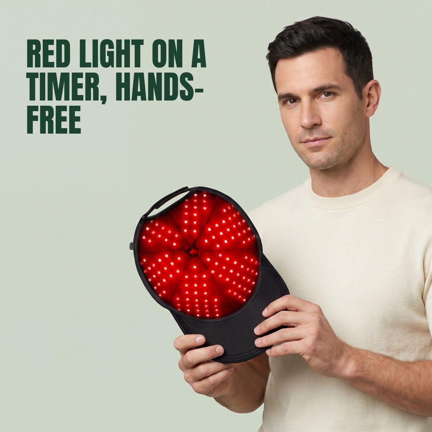 Man holding the infrared hair growth cap against a green background