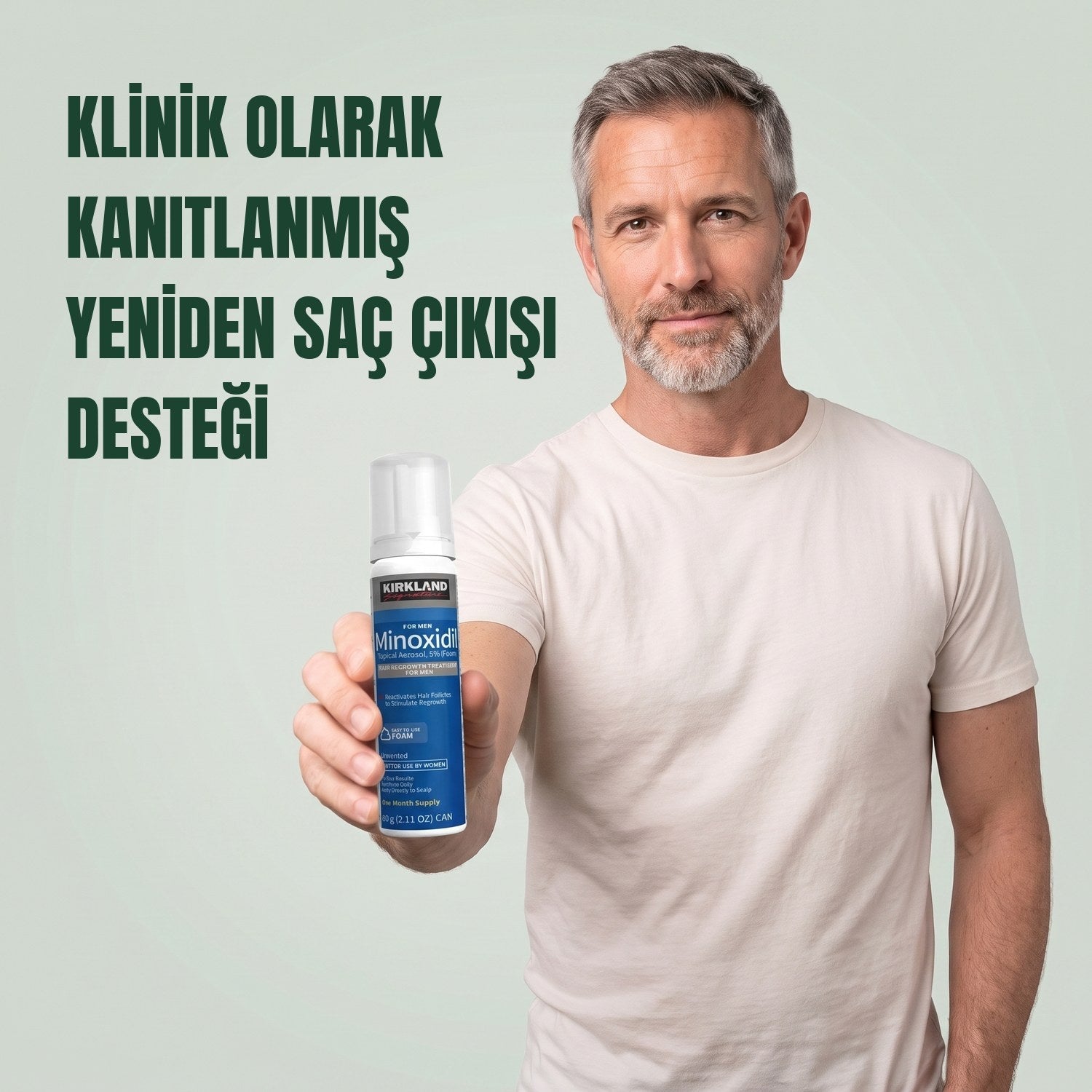 Yeşil arka plan önünde erkekler için Kirkland Signature Minoksidil 5% köpük kutusu tutan adam