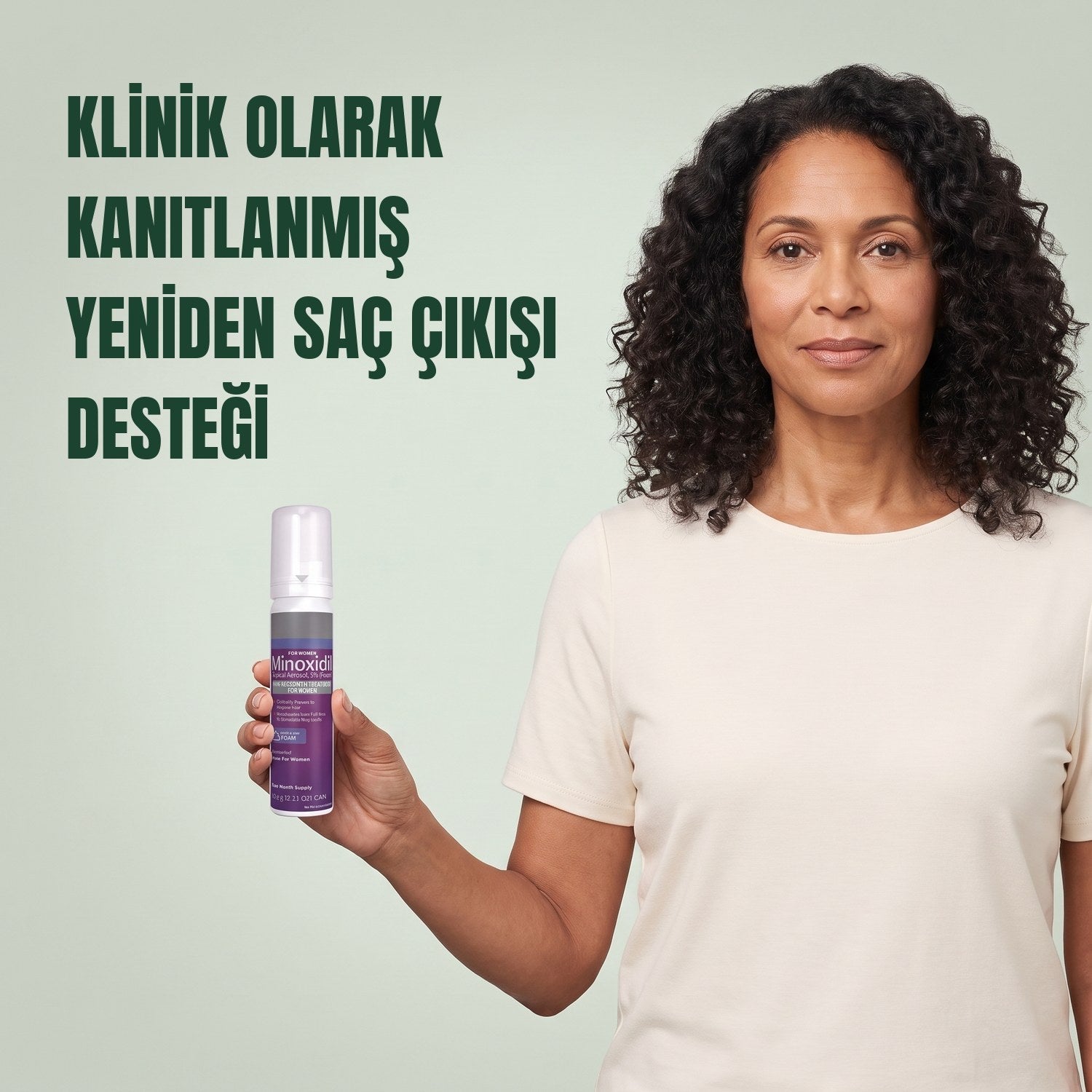 Yeşil arka plan önünde kadınlar için Kirkland Signature Minoksidil 5% köpük kutusu tutan kadın