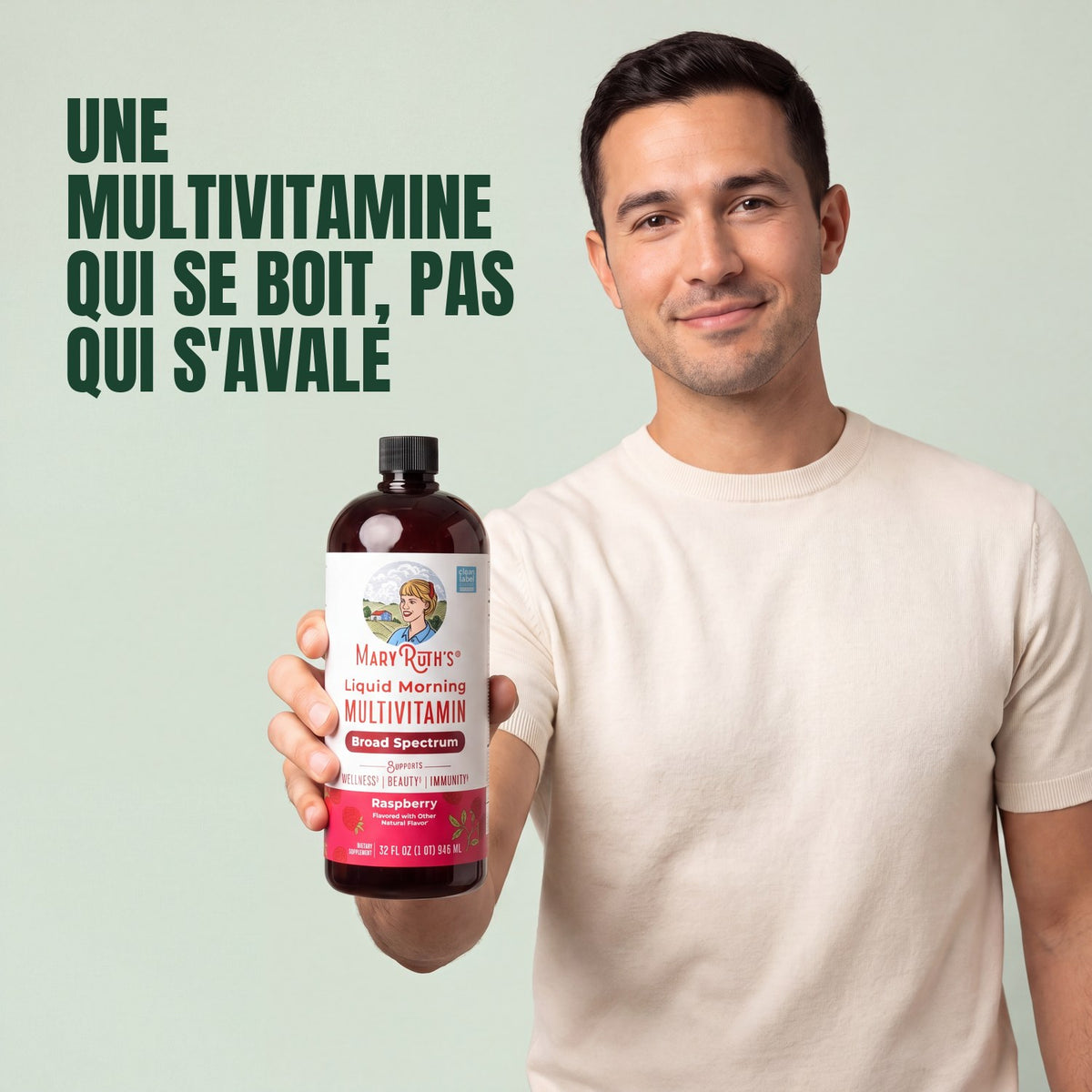 Man holding a MaryRuth Organics Liquid Morning Multivitamin raspberry bottle against a green background