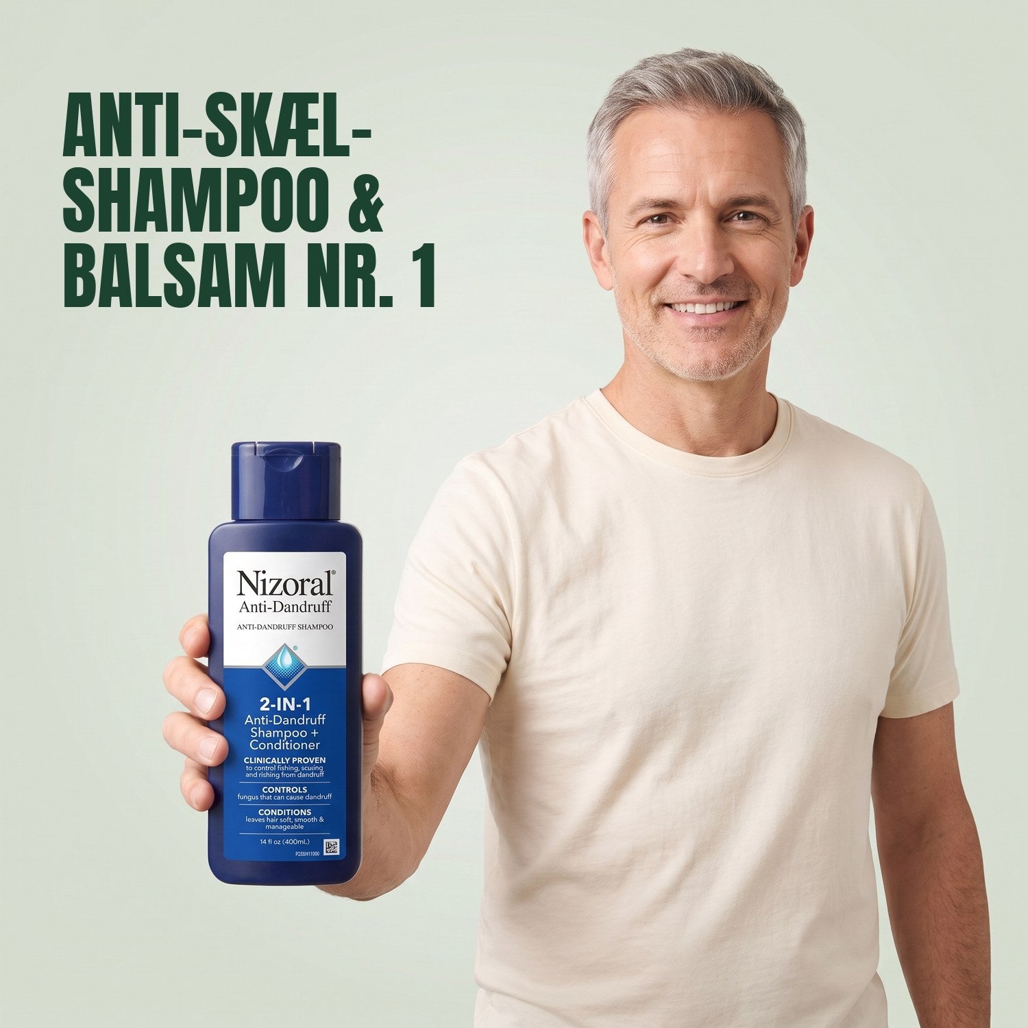Mand holder en Nizoral 2-i-1 anti-skæl shampoo og balsam-flaske mod en grøn baggrund