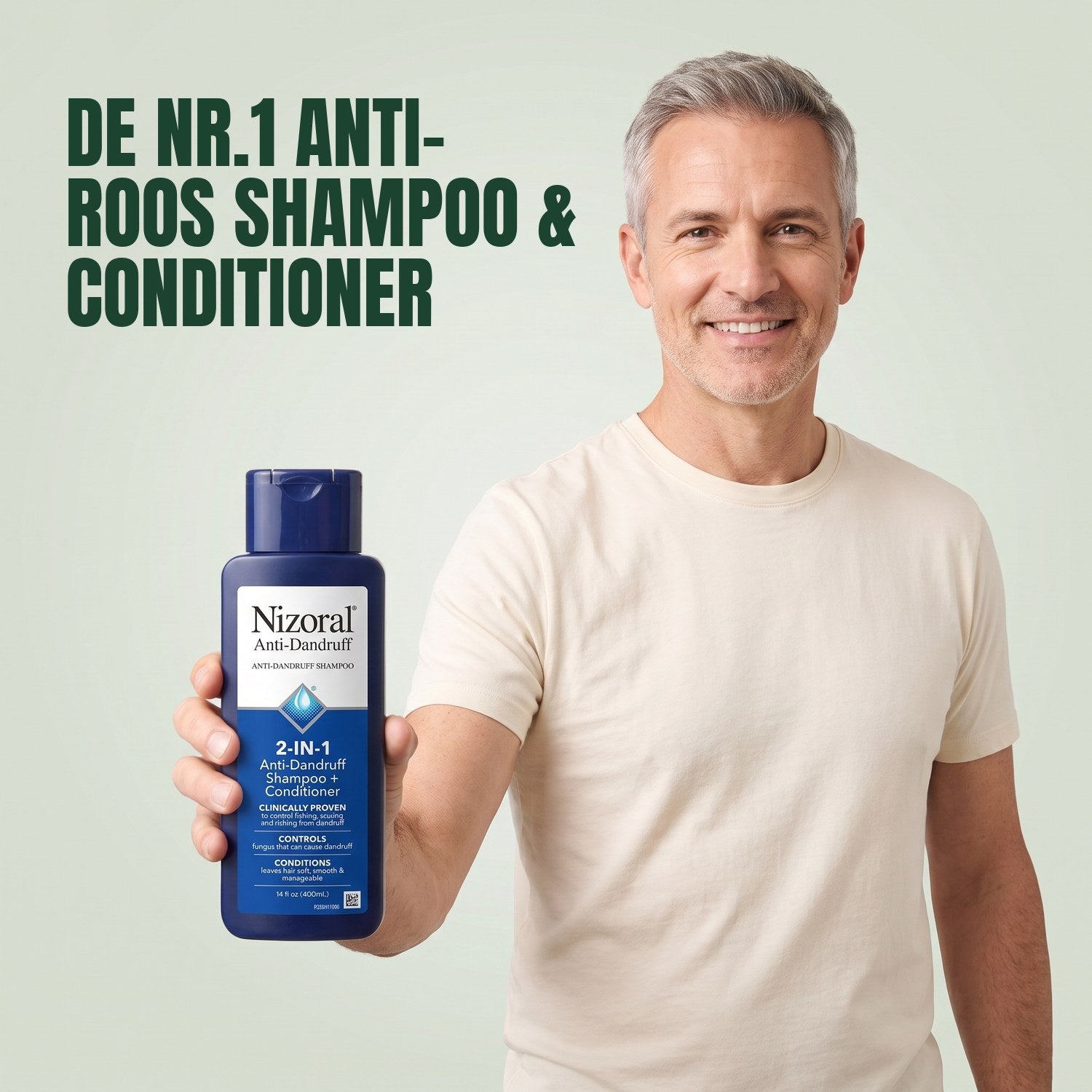 Man holding a Nizoral 2-in-1 anti-dandruff shampoo and conditioner bottle against a green background
