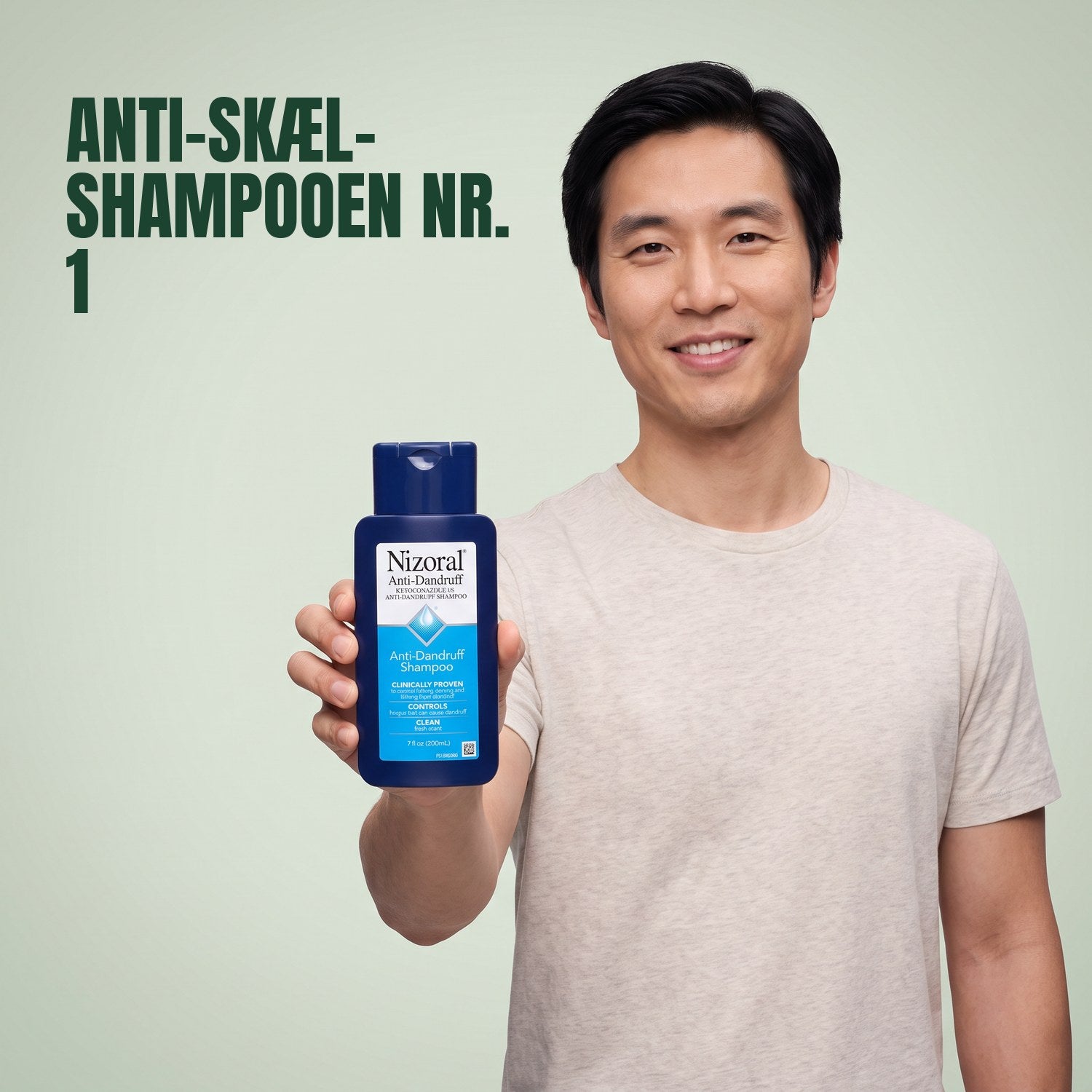 Mand holder en Nizoral anti-skæl shampoo 1%-flaske mod en grøn baggrund