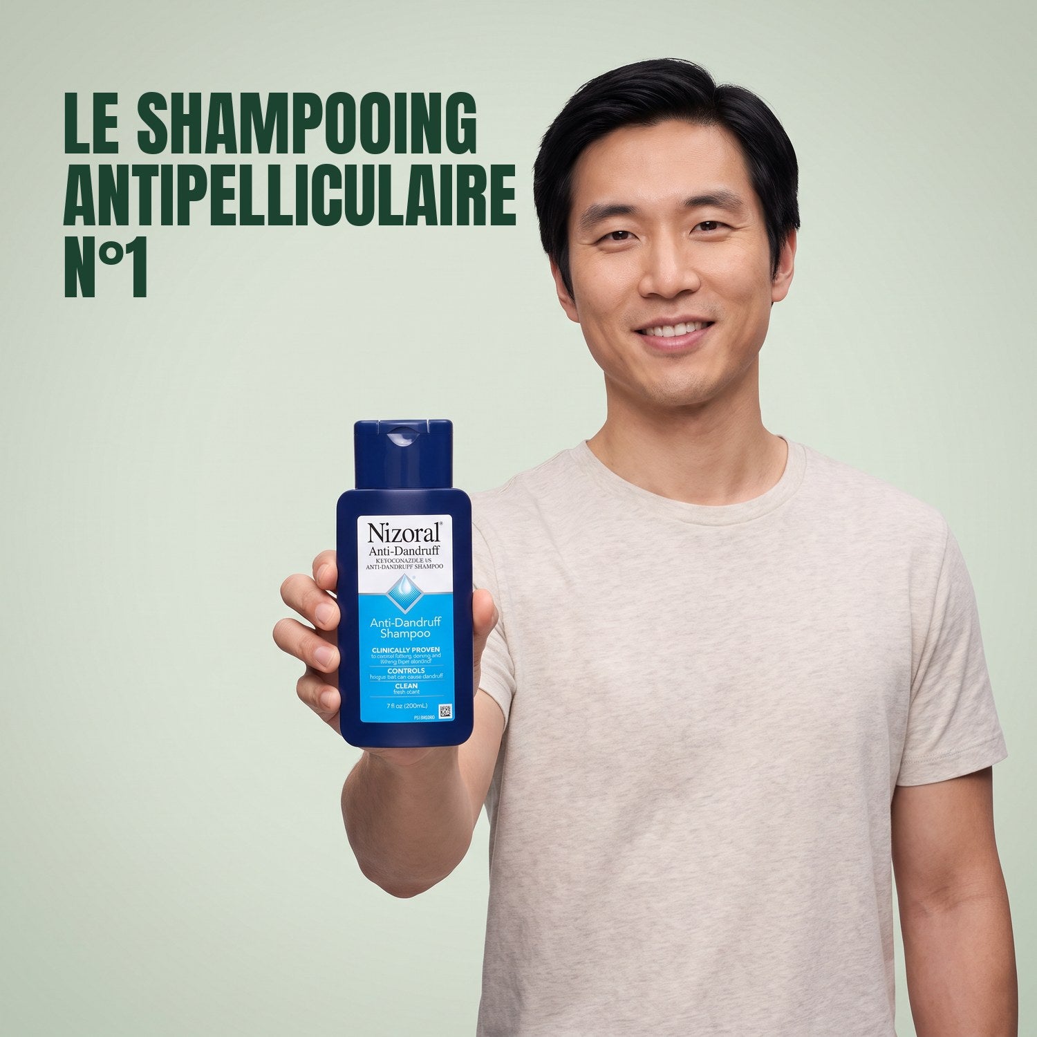 Man holding a Nizoral anti-dandruff shampoo 1% bottle against a green background