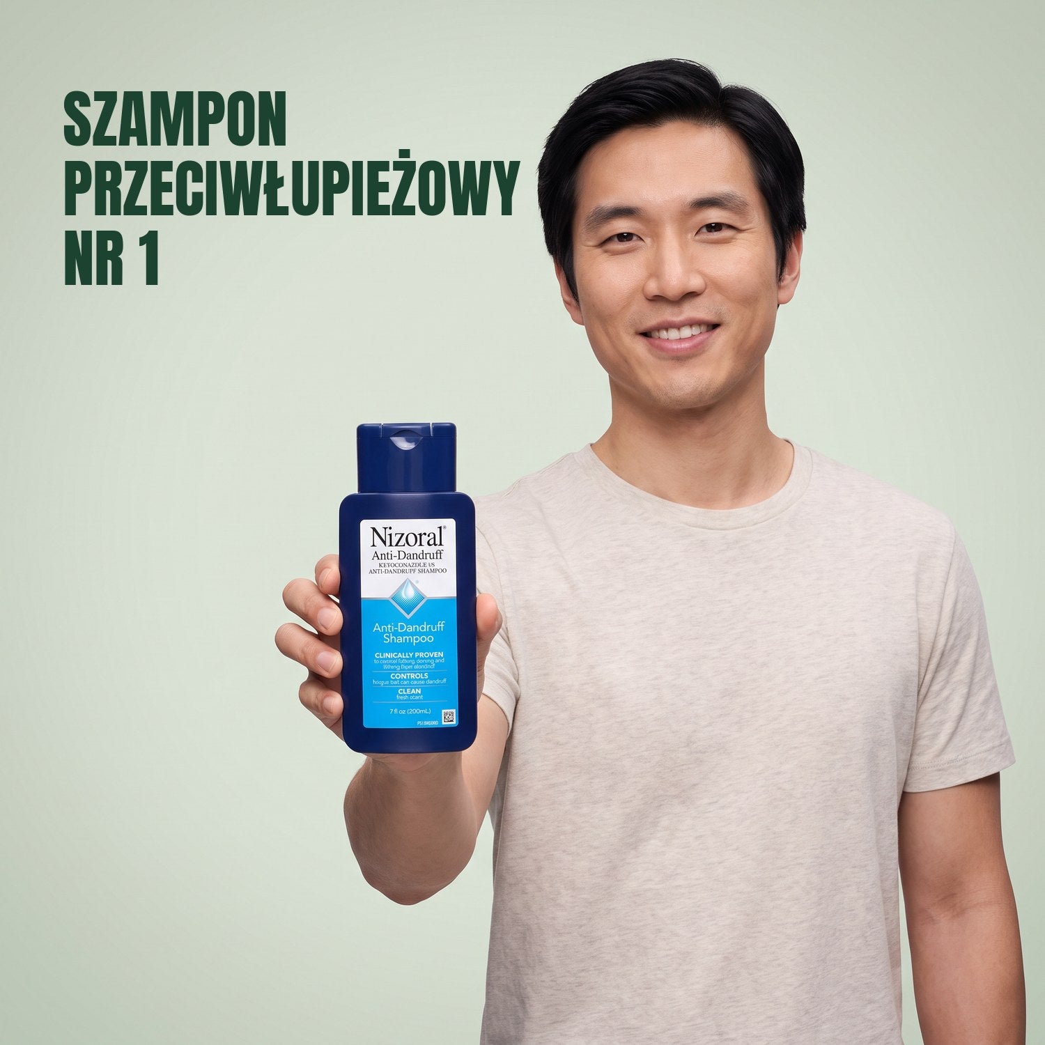 Mężczyzna trzyma butelkę szamponu przeciwłupieżowego Nizoral 1% na tle zielonego tła