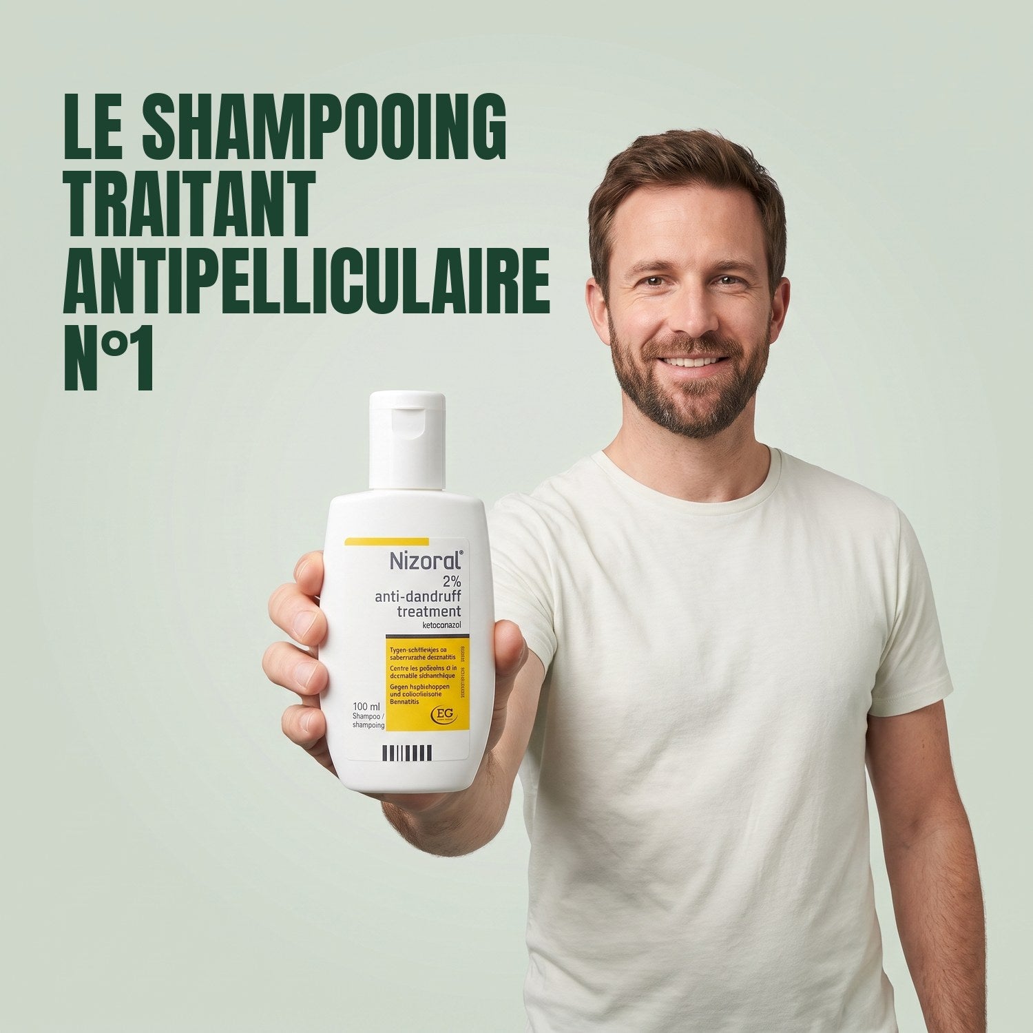 Man holding a Nizoral anti-dandruff treatment shampoo 2% 100 ml bottle against a green background
