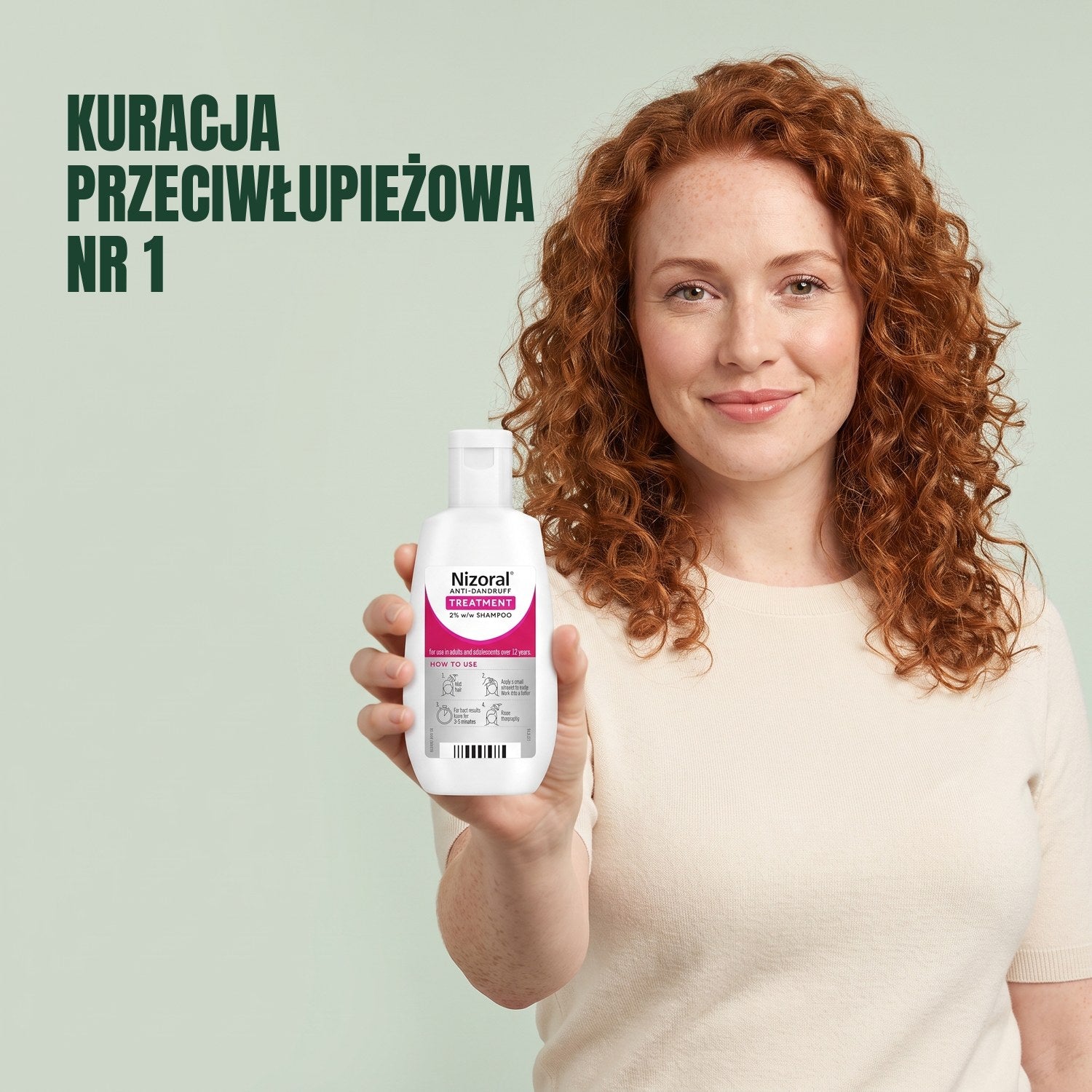 Kobieta trzyma butelkę szamponu przeciwłupieżowego Nizoral 2% na tle zielonego tła