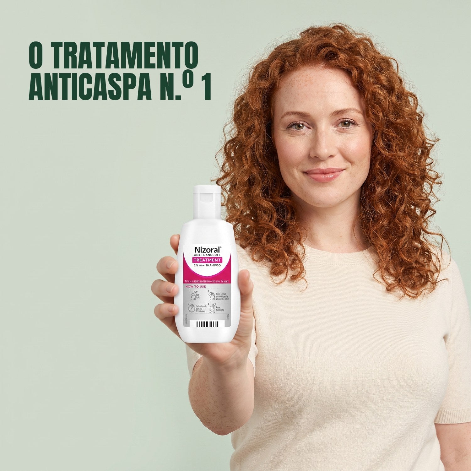 Mulher a segurar um frasco de champô de tratamento anticaspa Nizoral 2% sobre fundo verde