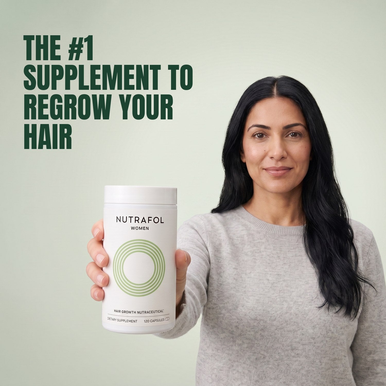 Woman holding the Nutrafol for Women 18-44 supplement box against a green background
