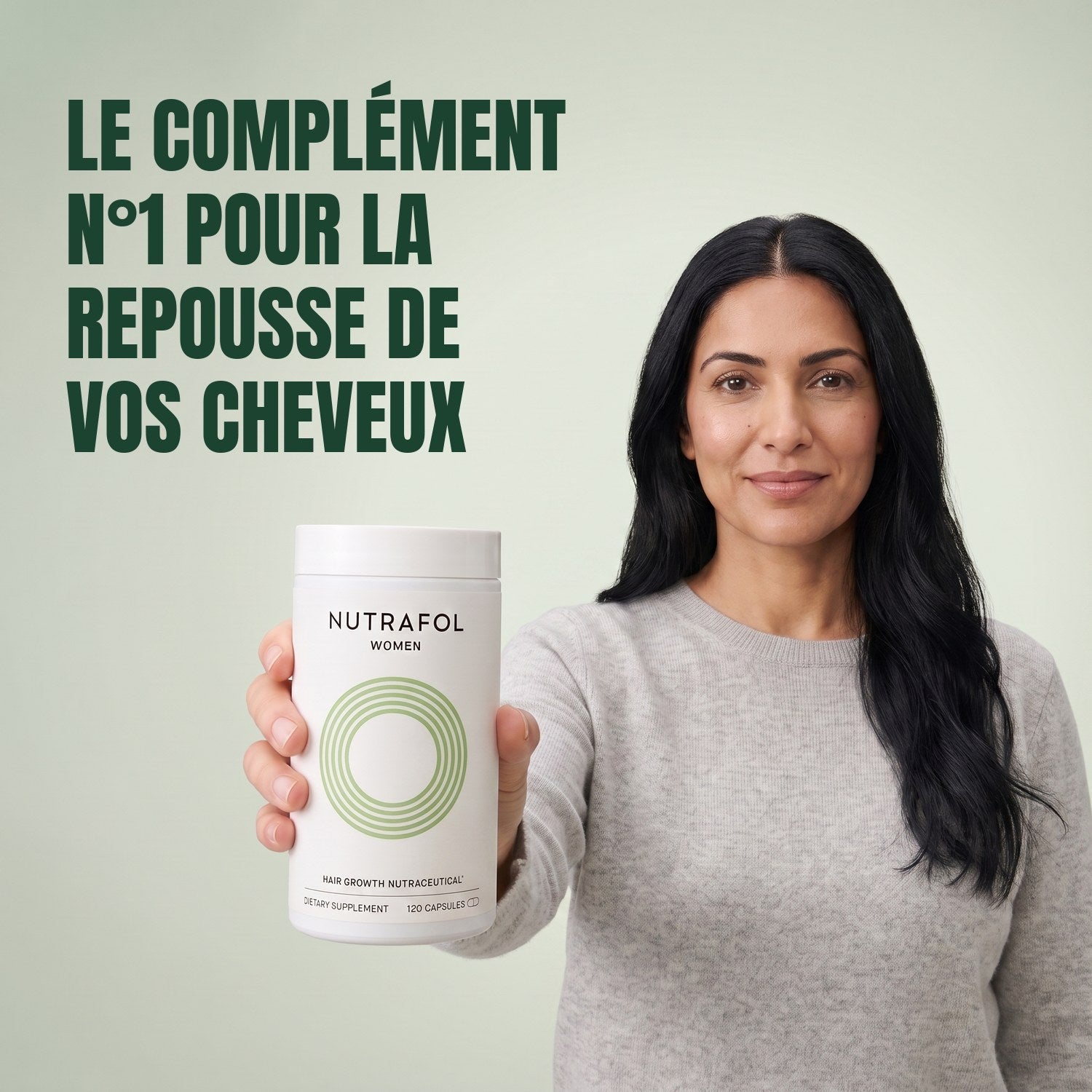Woman holding the Nutrafol for Women 18-44 supplement box against a green background