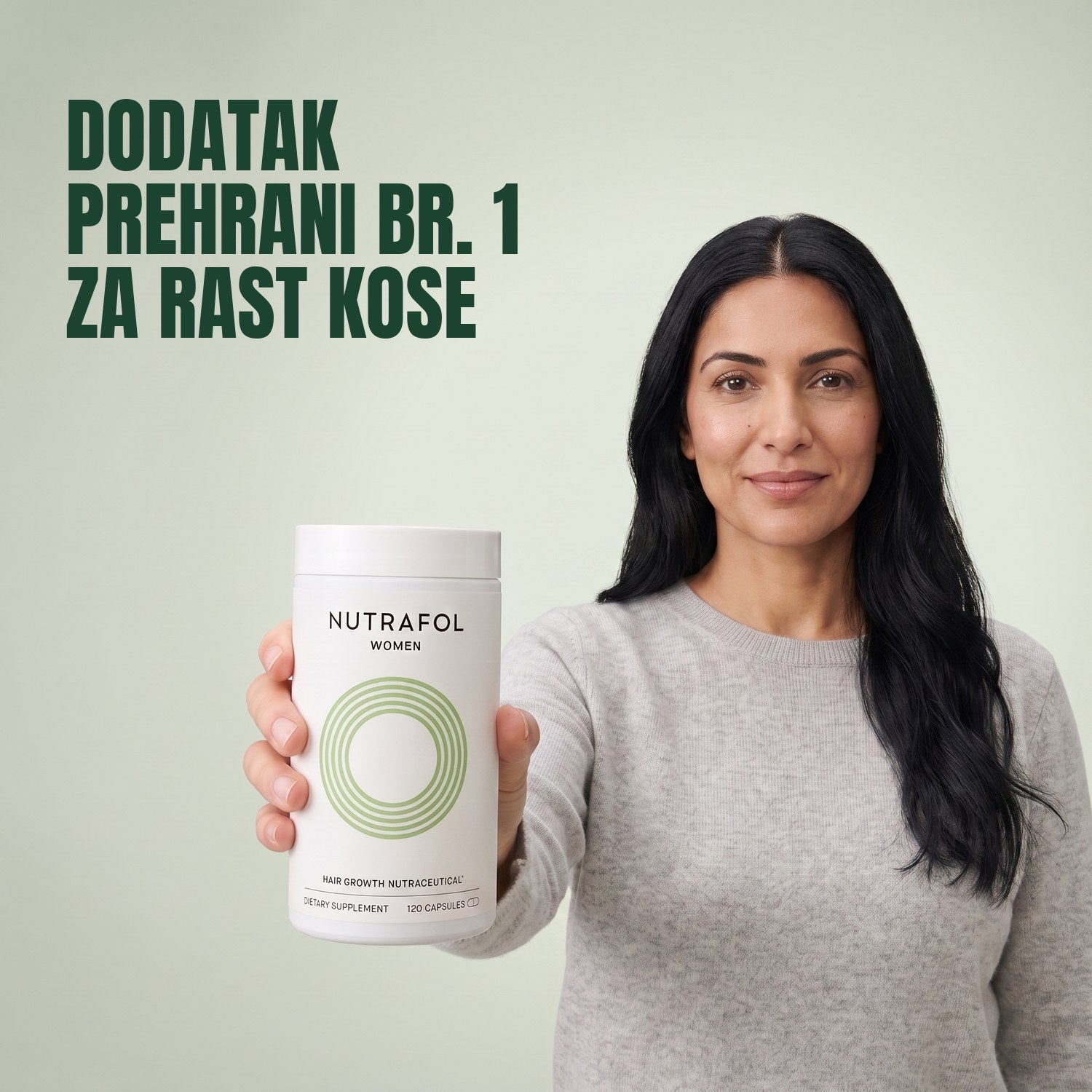 Žena drži kutiju dodatka prehrani Nutrafol for Women 18-44 na zelenoj pozadini