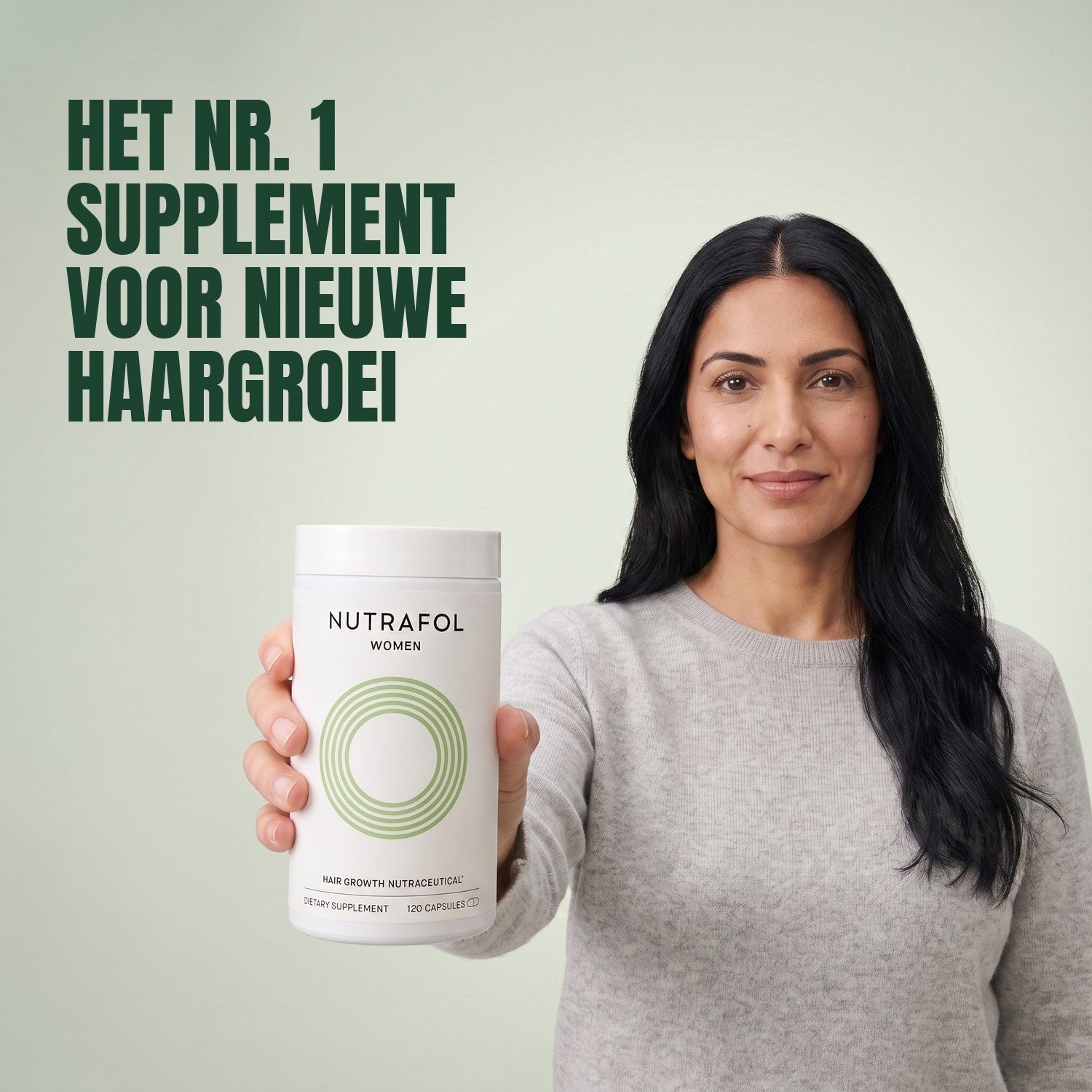 Woman holding the Nutrafol for Women 18-44 supplement box against a green background