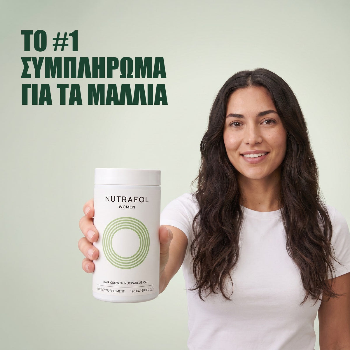 Γυναίκα κρατά το κουτί συμπληρώματος διατροφής Nutrafol for Women 18-44 σε πράσινο φόντο