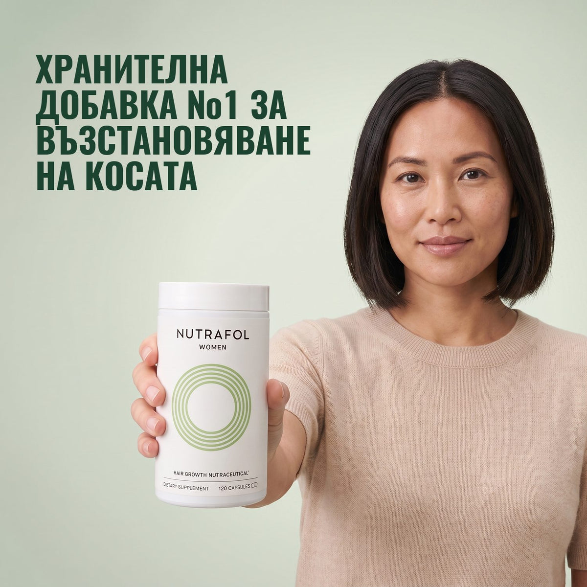 Жена държи кутия хранителна добавка Nutrafol for Women 18-44 на зелен фон