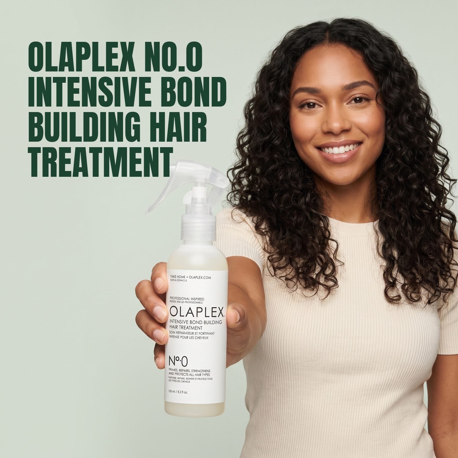 Woman holding Olaplex No.0 Intensive Bond Building Hair Treatment against a green background