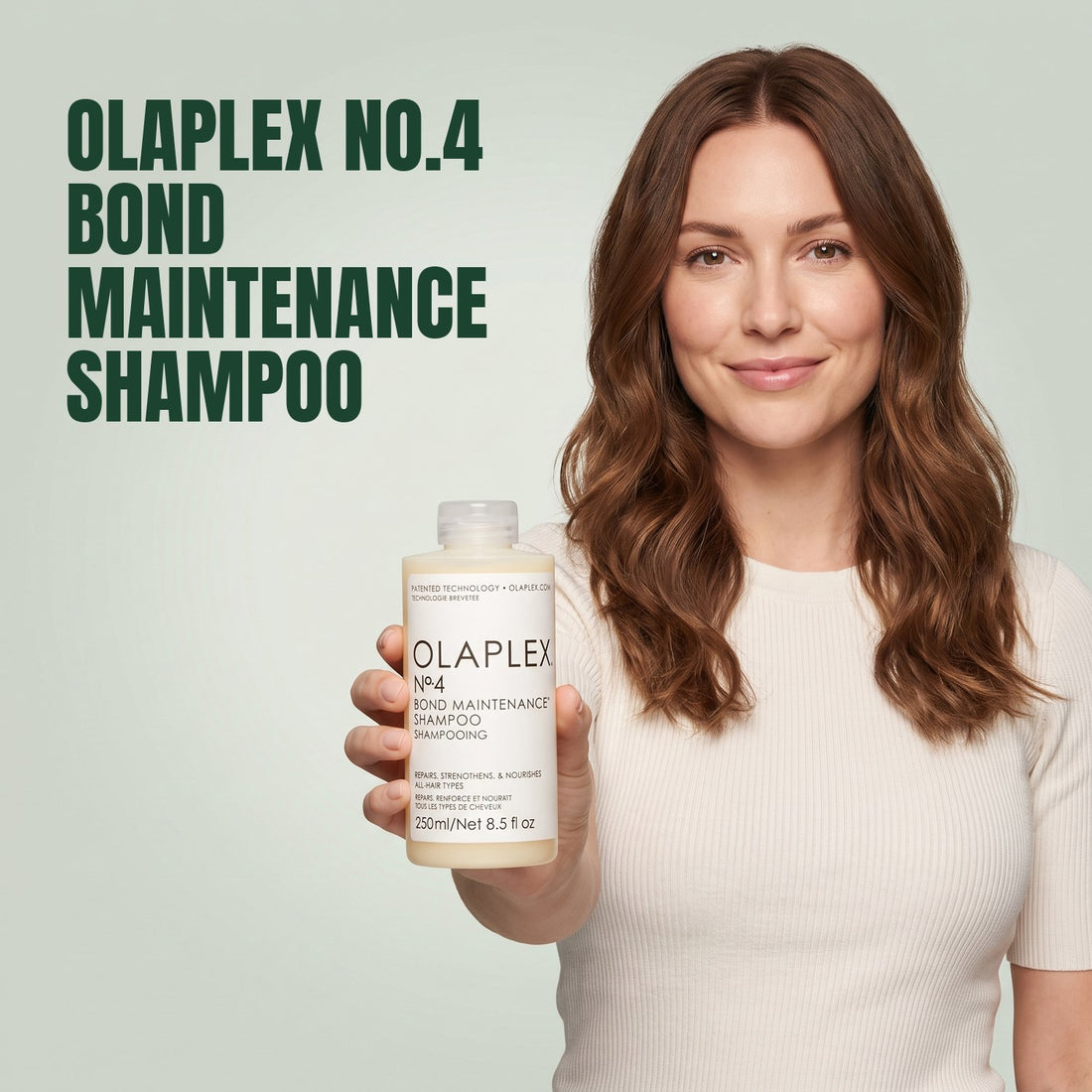 Woman holding Olaplex No.4 Bond Maintenance Shampoo against a green background
