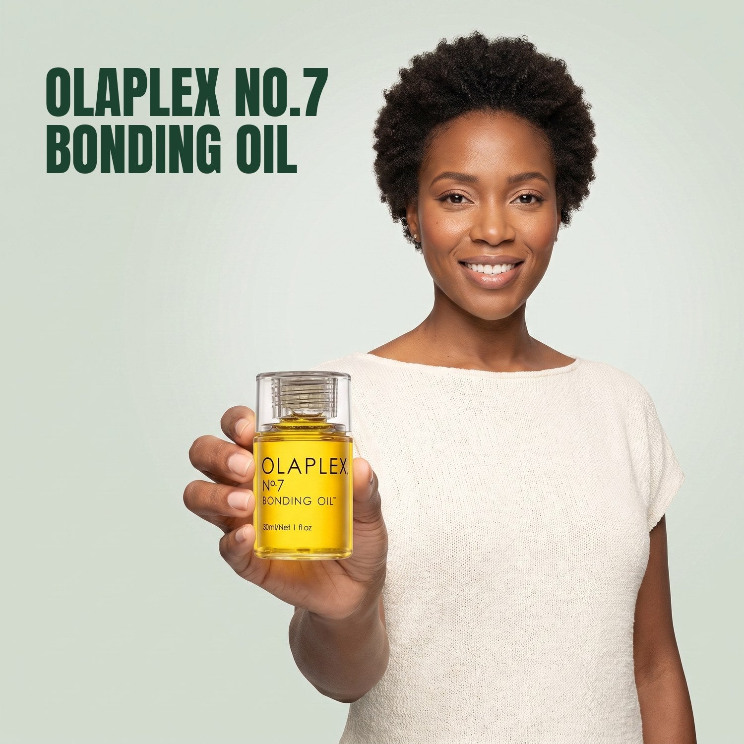 Woman holding Olaplex No.7 Bonding Oil against a green background