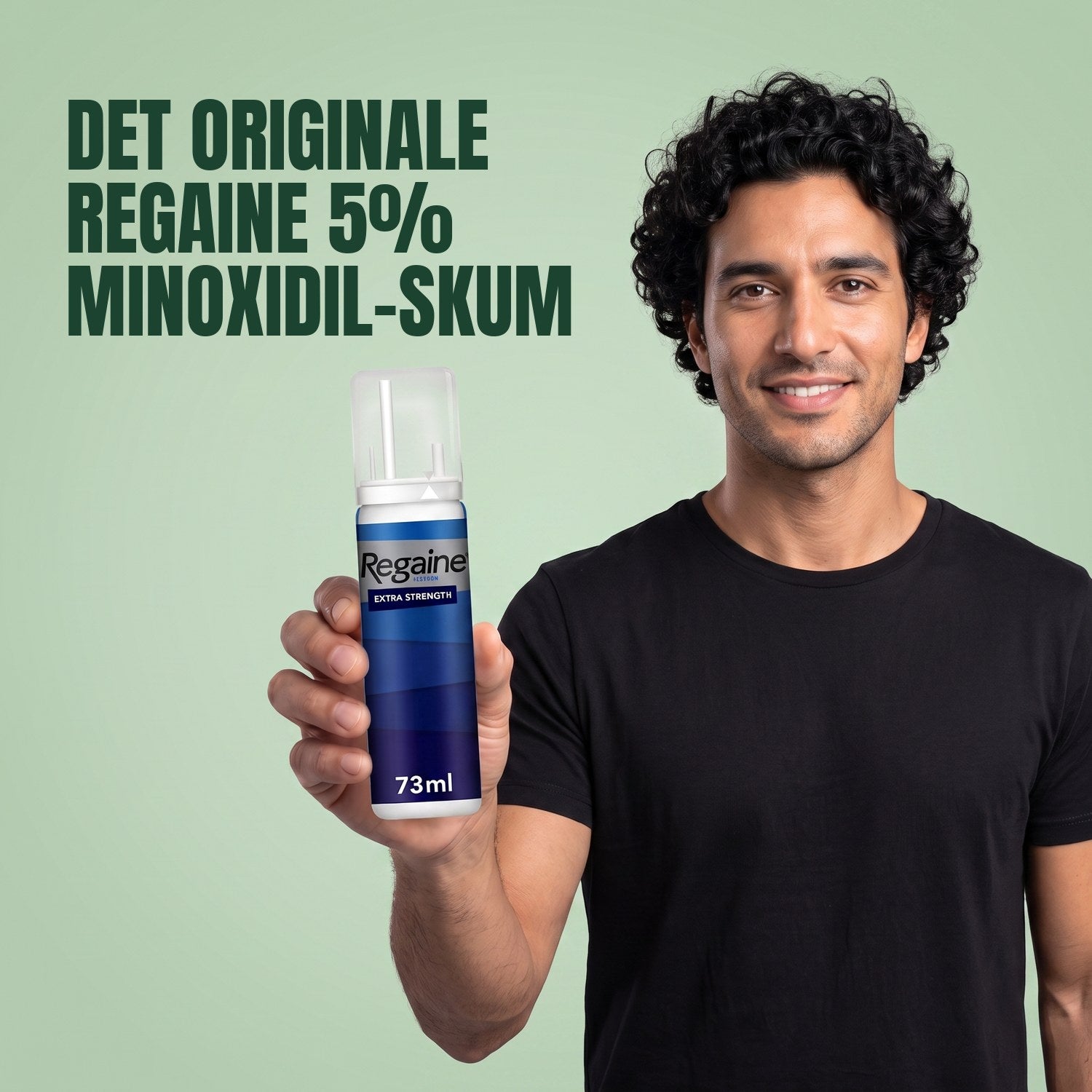 Man holding the Regaine for Men Minoxidil 5% foam pack against a green background