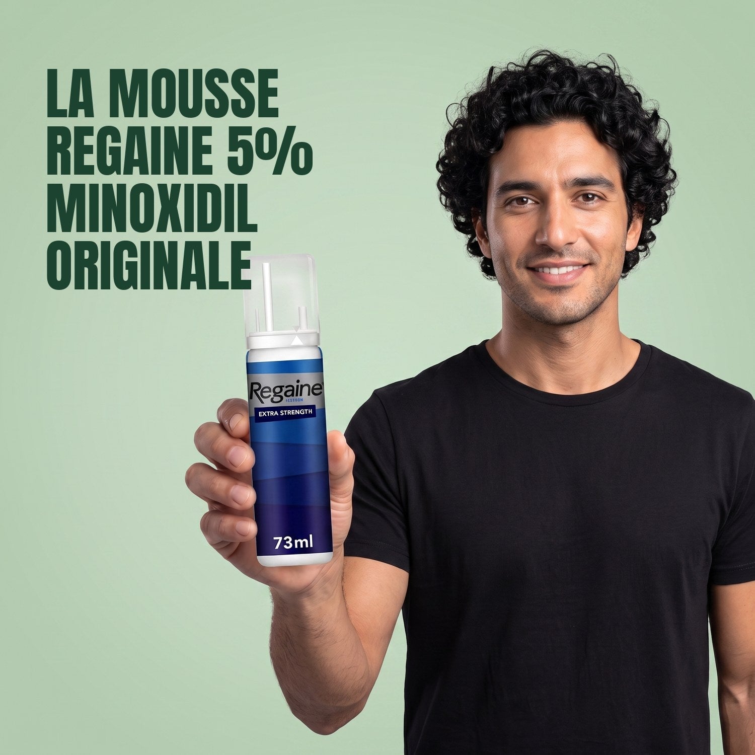 Man holding the Regaine for Men Minoxidil 5% foam pack against a green background