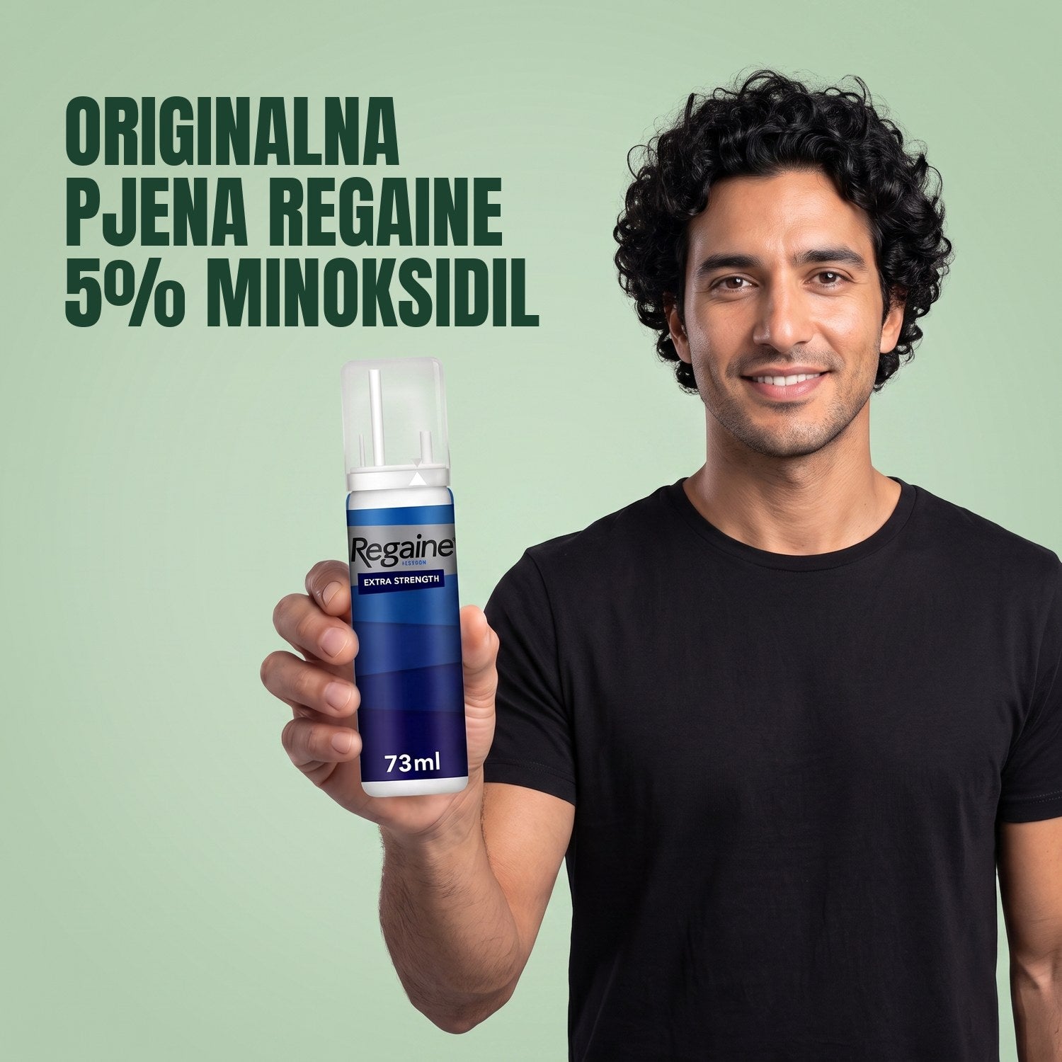 Muškarac drži pakiranje Regaine for Men Minoxidil 5% pjene na zelenoj pozadini