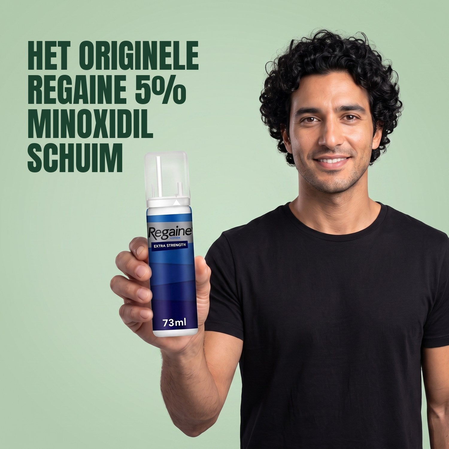 Man holding the Regaine for Men Minoxidil 5% foam pack against a green background