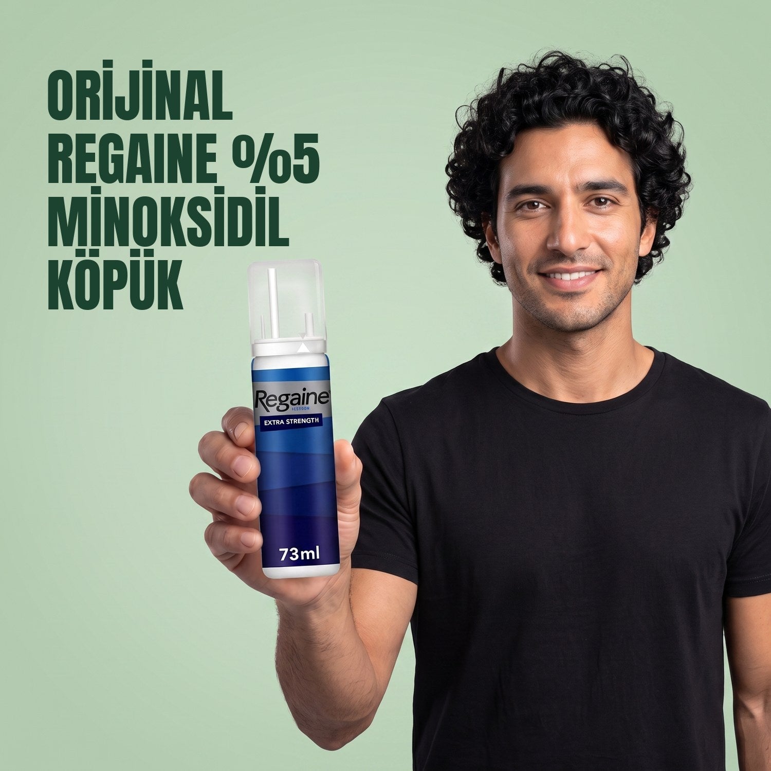 Man holding the Regaine for Men Minoxidil 5% foam pack against a green background