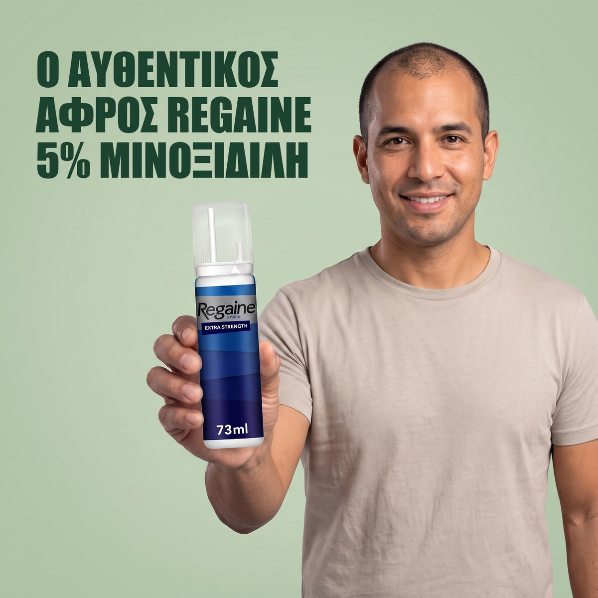Άντρας κρατά τη συσκευασία Regaine for Men Minoxidil 5% αφρός σε πράσινο φόντο