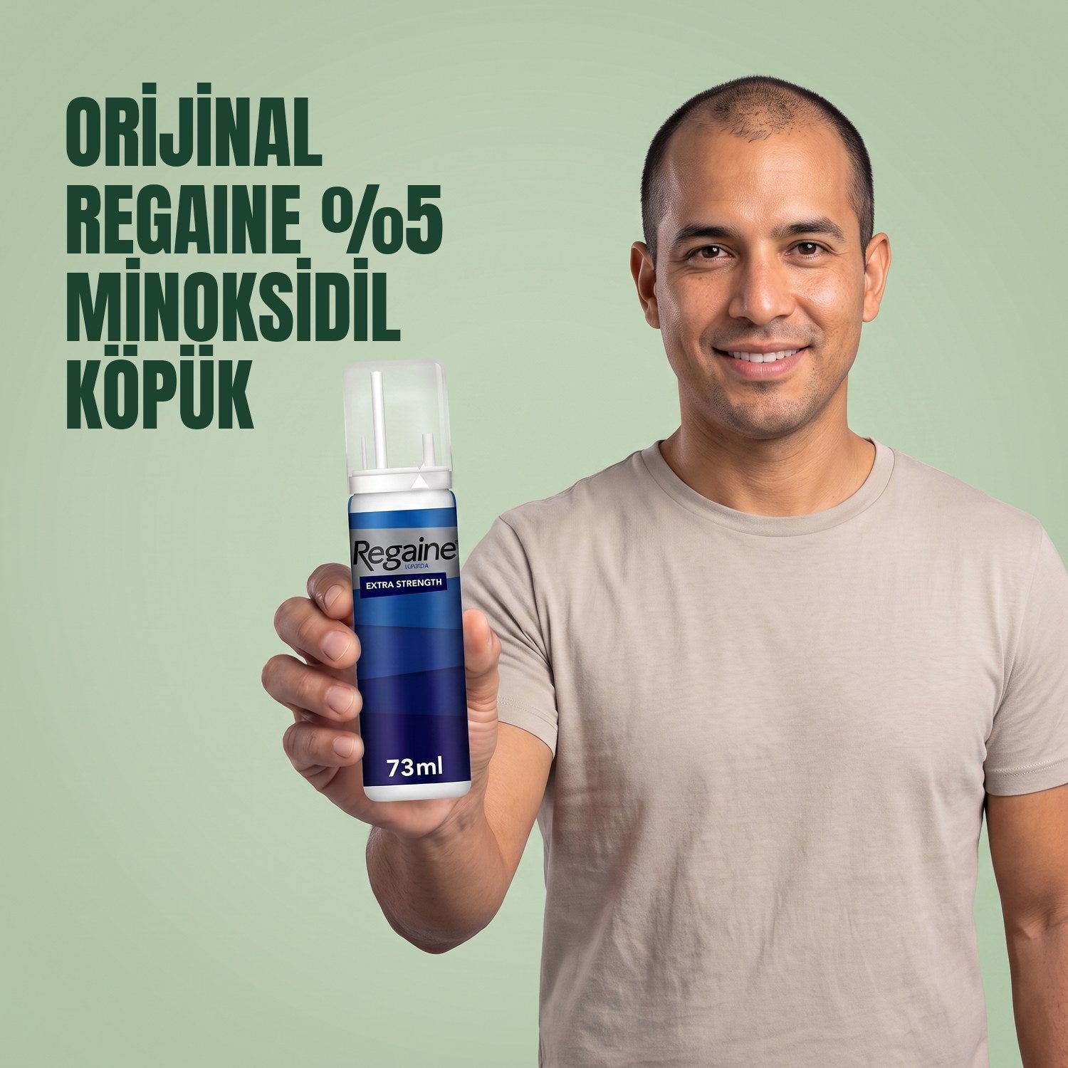 Man holding the Regaine for Men Minoxidil 5% foam pack against a green background