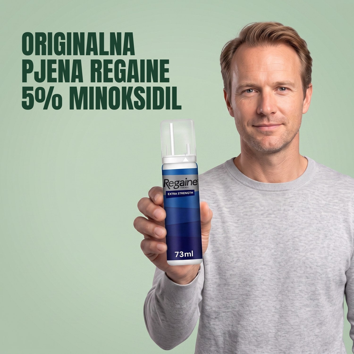 Muškarac drži pakiranje Regaine for Men Minoxidil 5% pjene na zelenoj pozadini