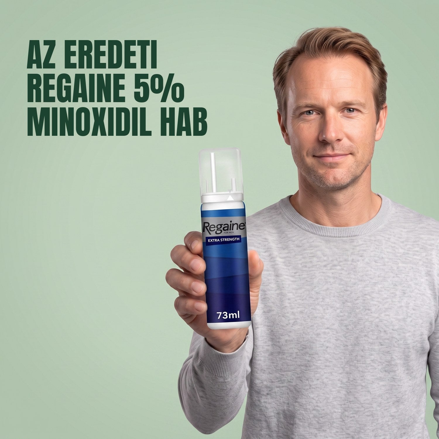 Férfi tartja a Regaine for Men Minoxidil 5% hab csomagját, zöld háttér előtt