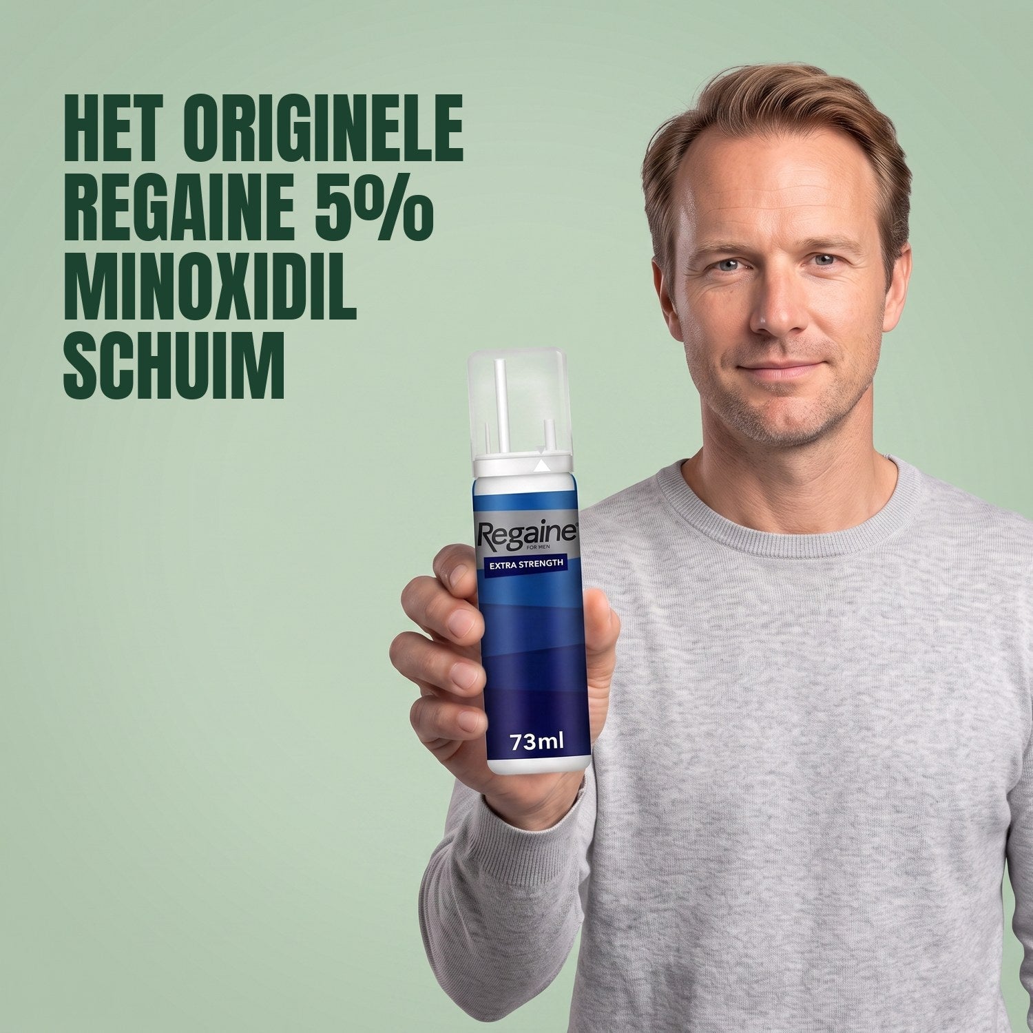 Man holding the Regaine for Men Minoxidil 5% foam pack against a green background