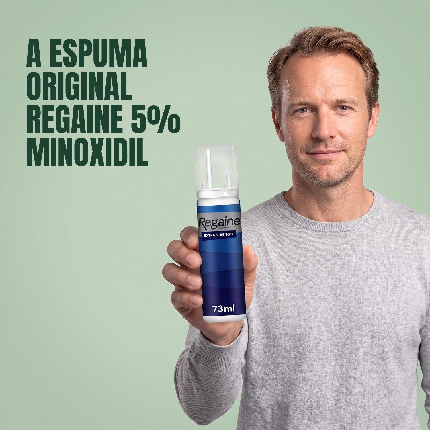 Man holding the Regaine for Men Minoxidil 5% foam pack against a green background