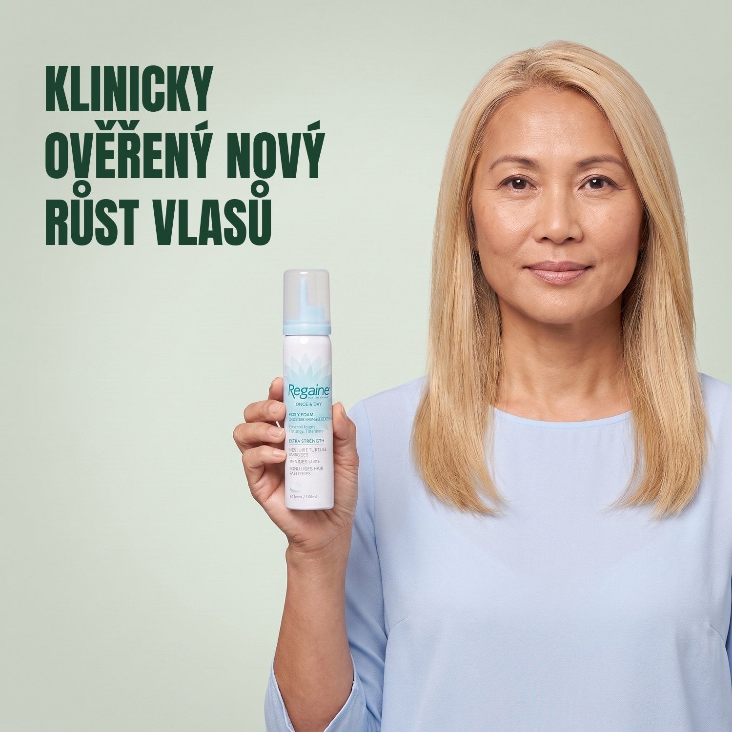 Žena drží krabičku pěny Regaine for Women Minoxidil 5% s plechovkou pěny na zeleném pozadí