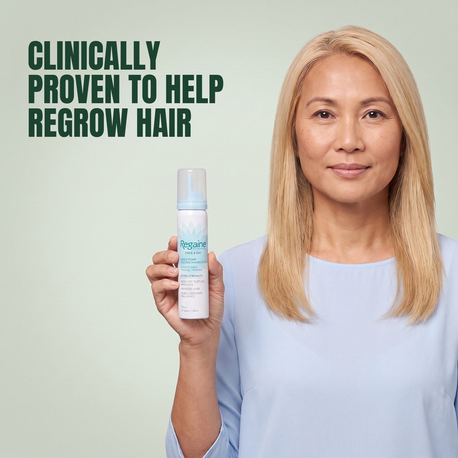 Woman holding the Regaine for Women Minoxidil 5% foam carton with a foam can against a green background