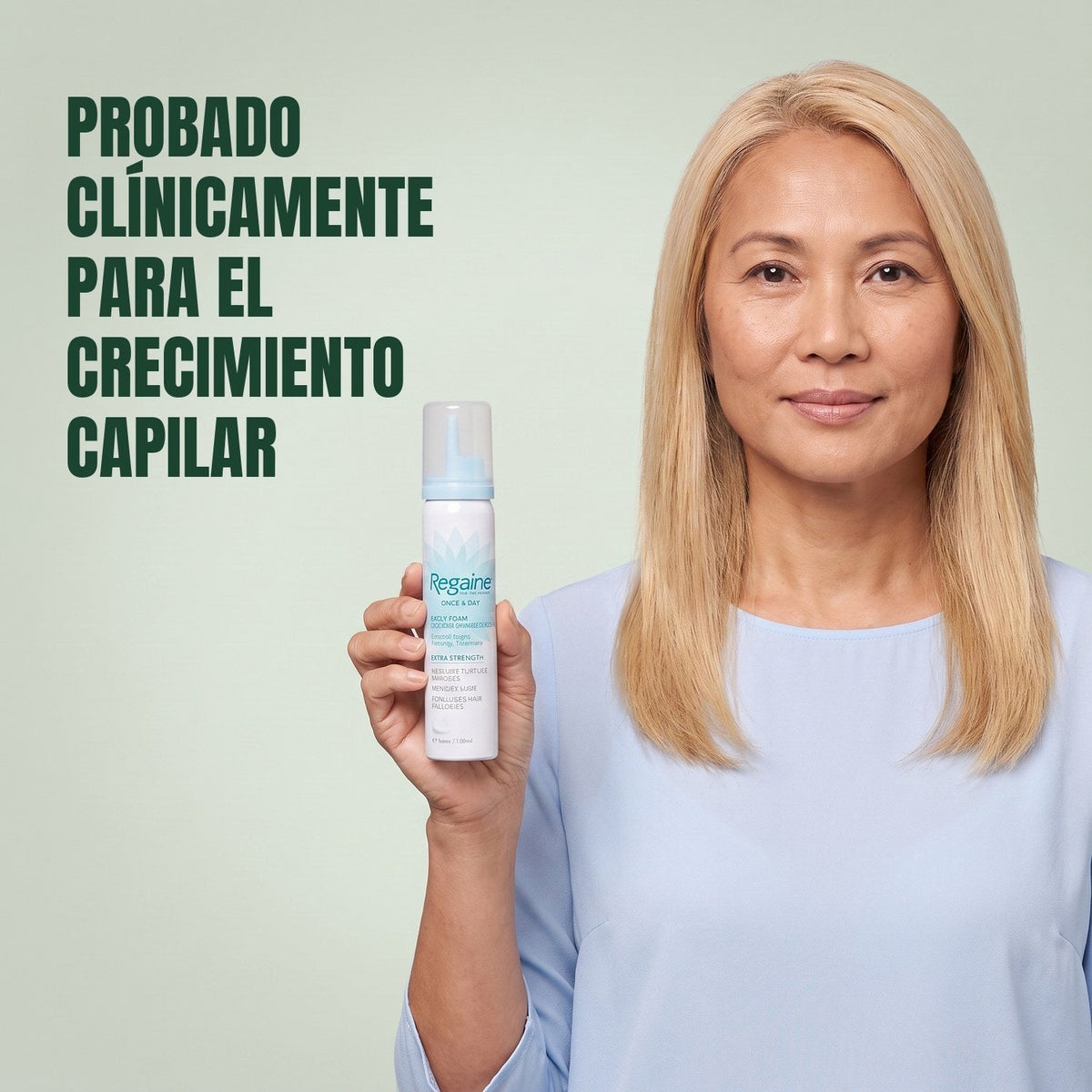 Woman holding the Regaine for Women Minoxidil 5% foam carton with a foam can against a green background