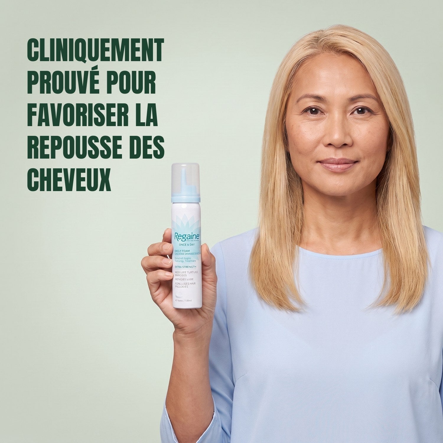 Woman holding the Regaine for Women Minoxidil 5% foam carton with a foam can against a green background