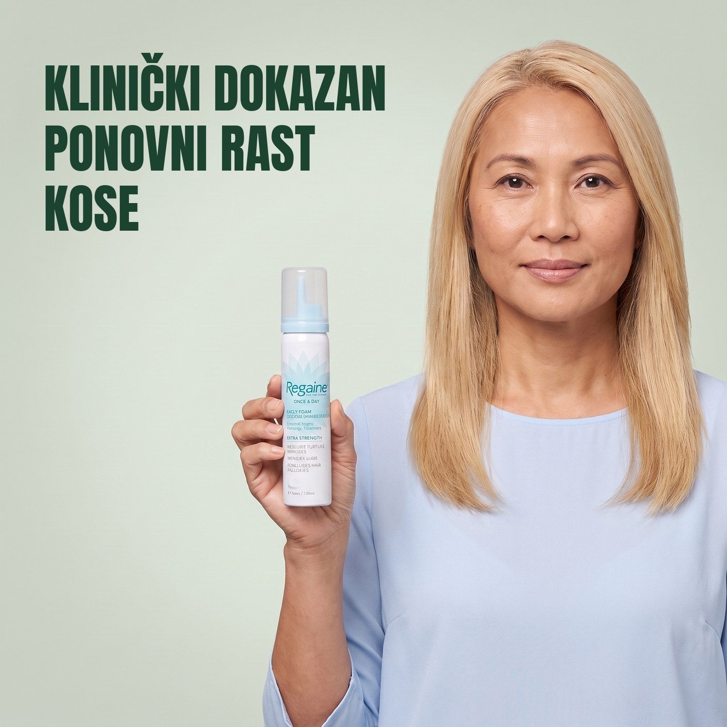 Žena drži kutiju Regaine for Women Minoxidil 5% pjene s limenkom pjene na zelenoj pozadini