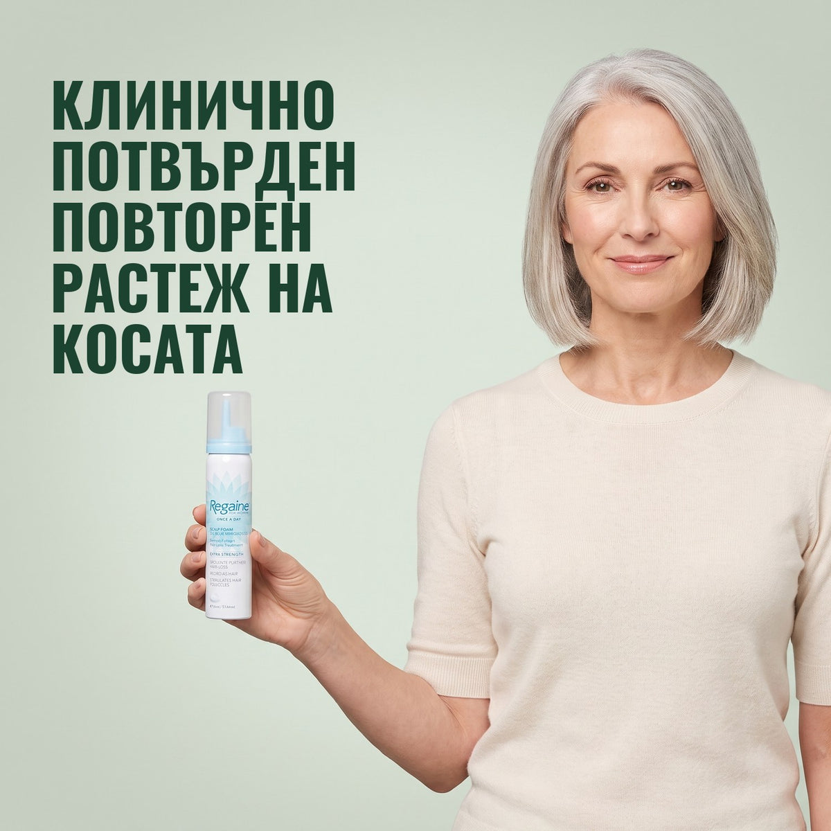 Жена държи кутия Regaine for Women Minoxidil 5% пяна на зелен фон