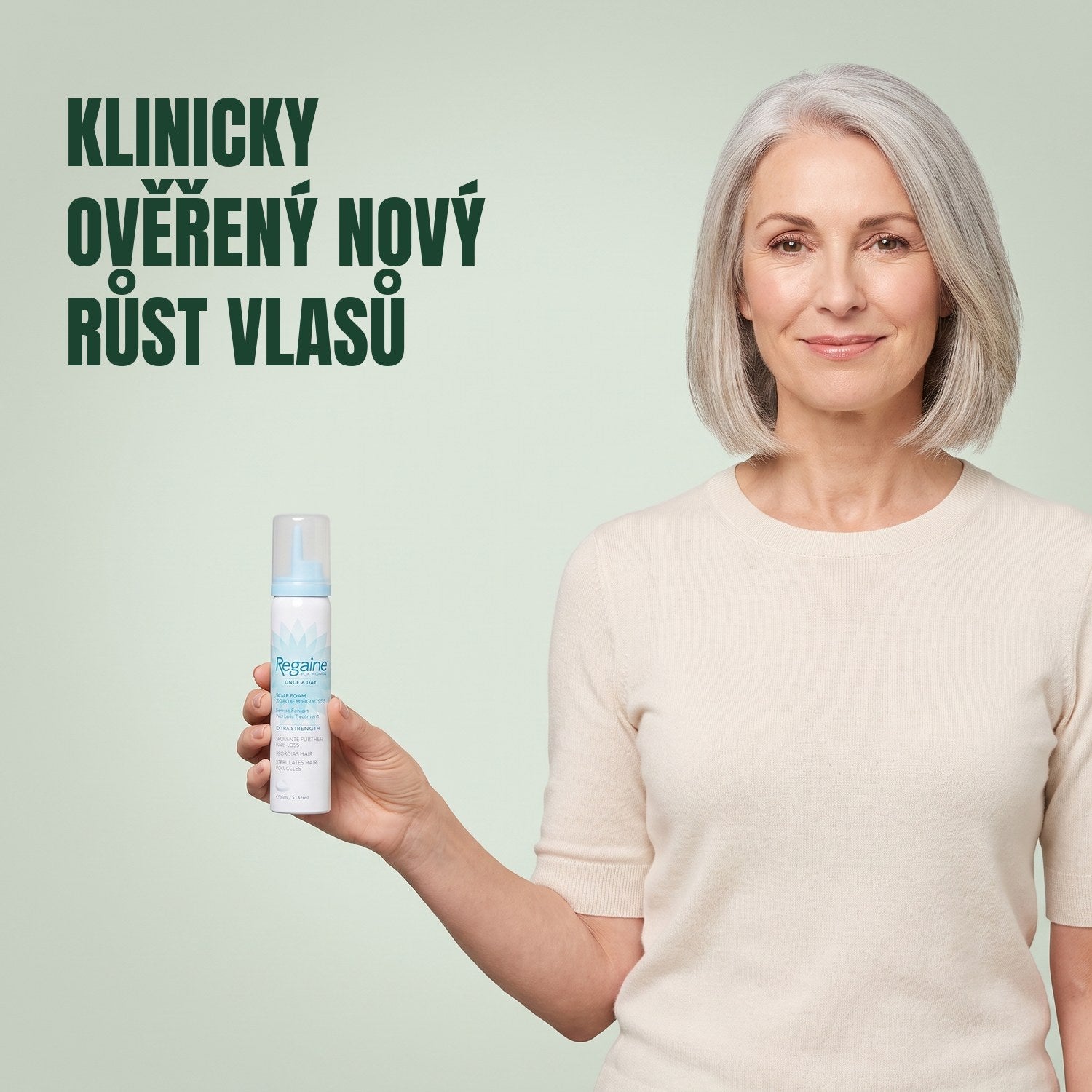 Žena drží plechovku pěny Regaine for Women Minoxidil 5% na zeleném pozadí