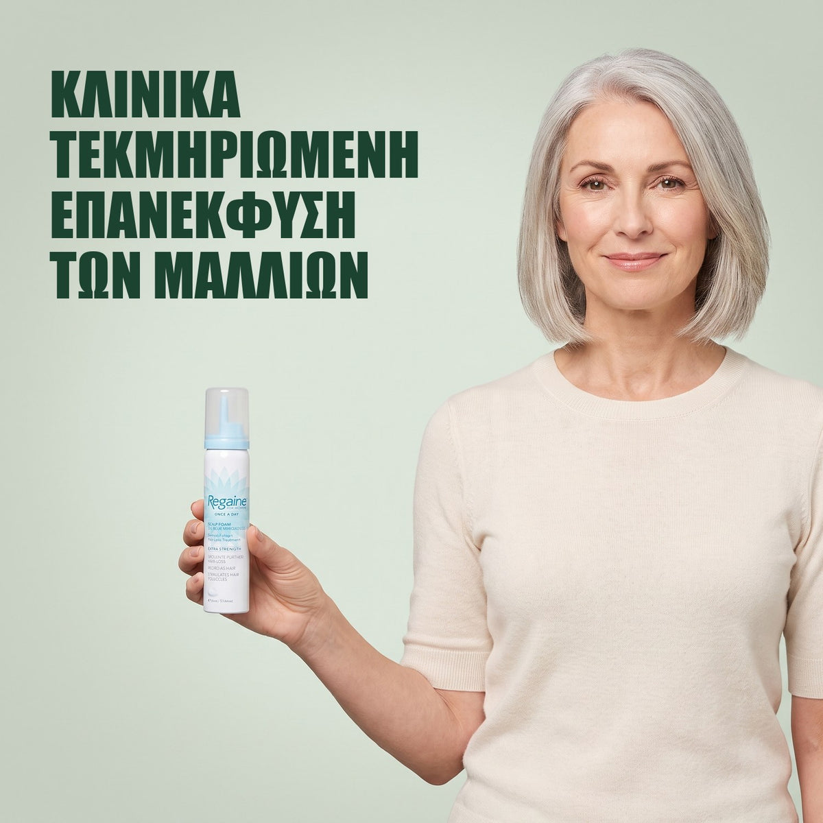 Γυναίκα κρατά δοχείο αφρού Regaine for Women Minoxidil 5% σε πράσινο φόντο