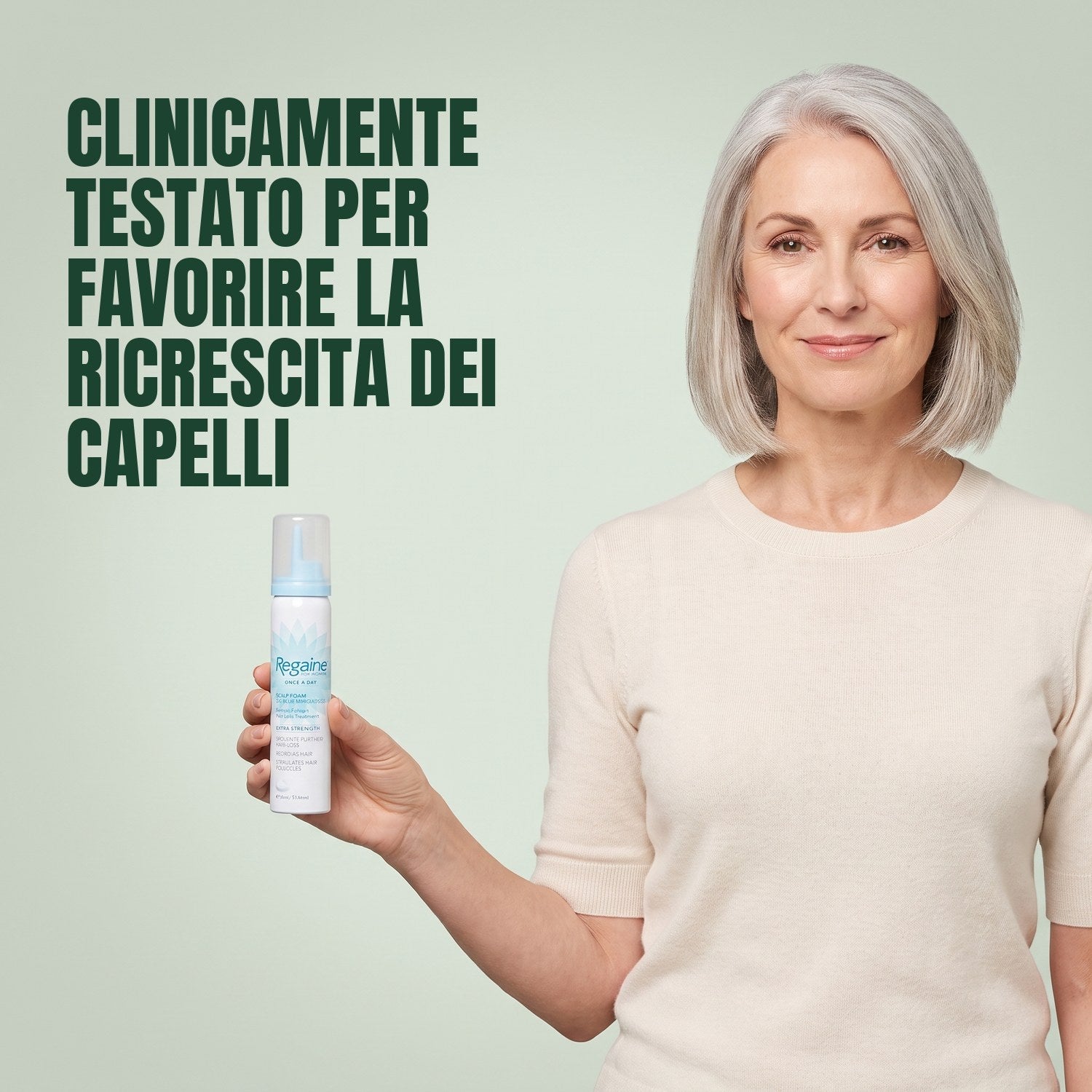 Woman holding a Regaine for Women Minoxidil 5% foam can against a green background