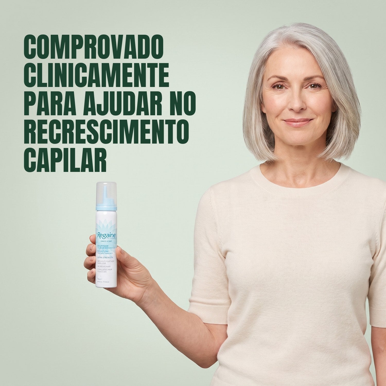 Mulher segurando uma lata de espuma Regaine for Women Minoxidil 5% contra um fundo verde