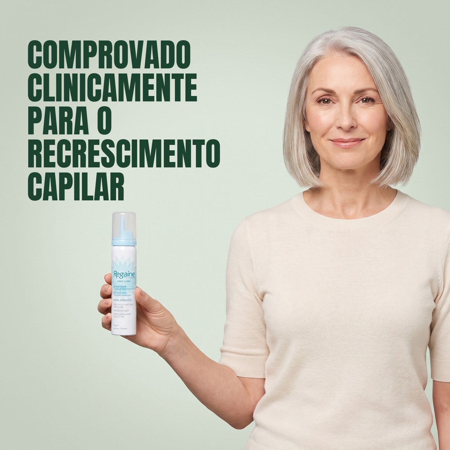 Mulher a segurar uma lata de espuma Regaine para Mulher Minoxidil 5% sobre fundo verde