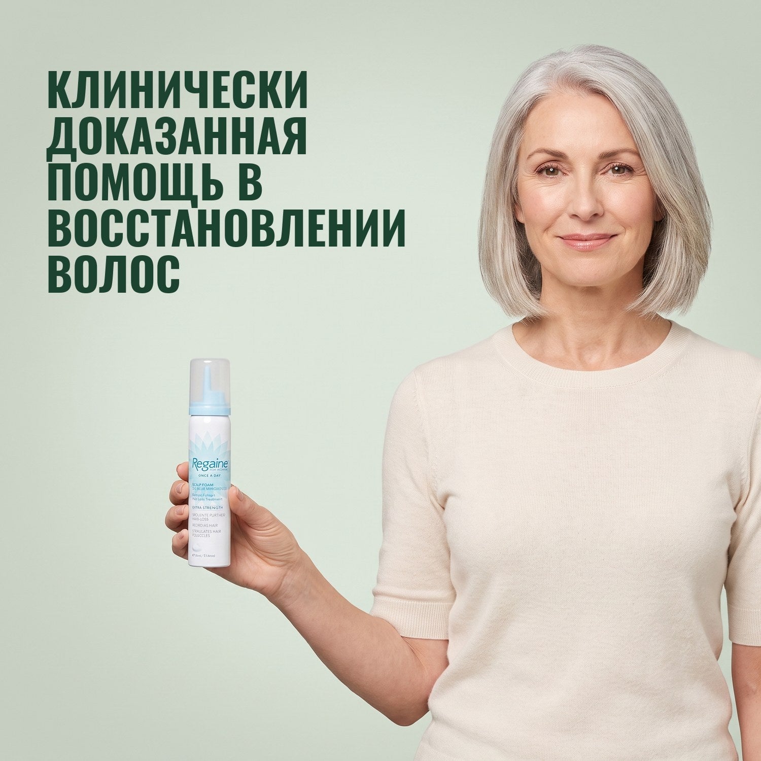 Женщина держит баллон пены Regaine для женщин с миноксидилом 5% на зелёном фоне