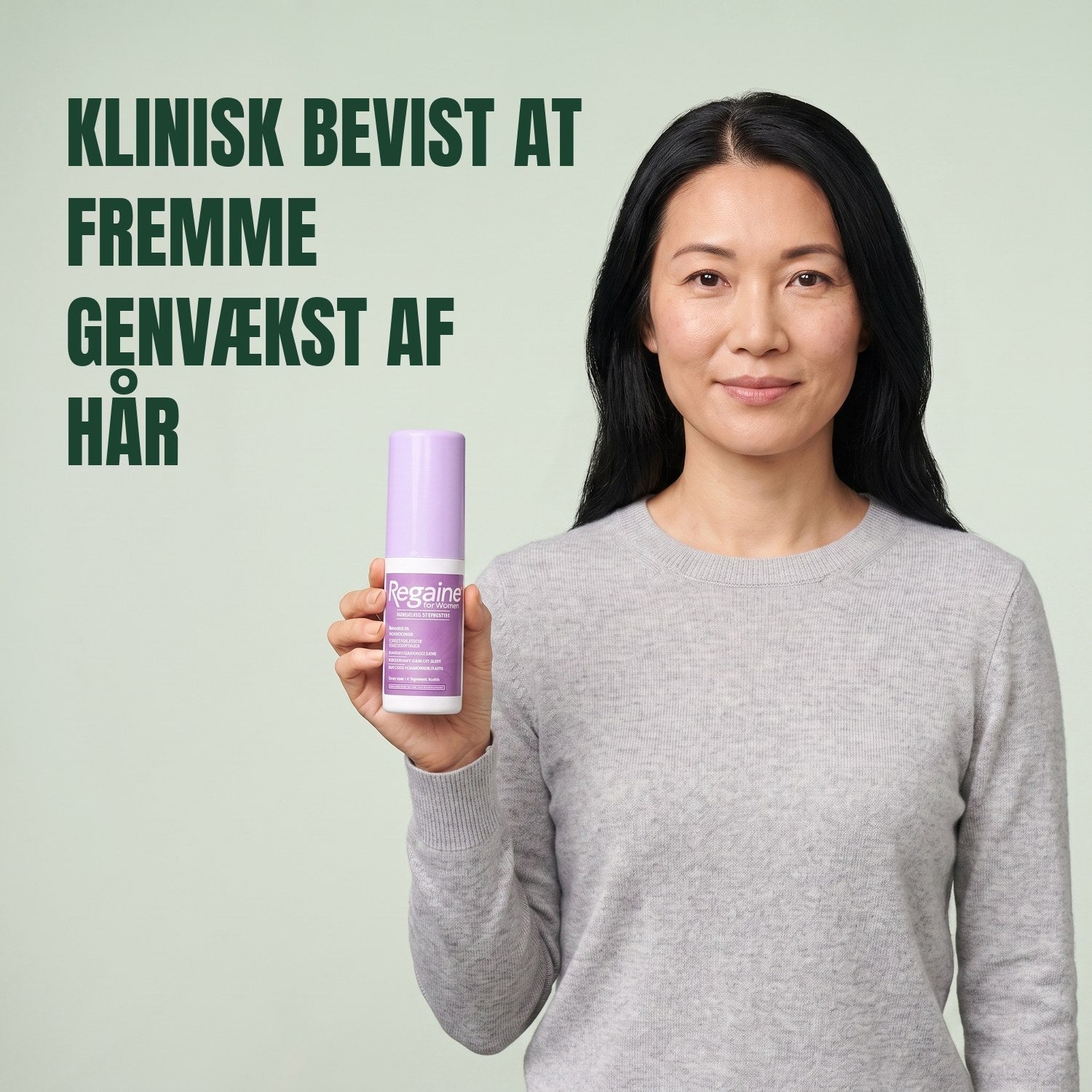 Woman holding the Regaine for Women Minoxidil 2% lotion pack against a green background
