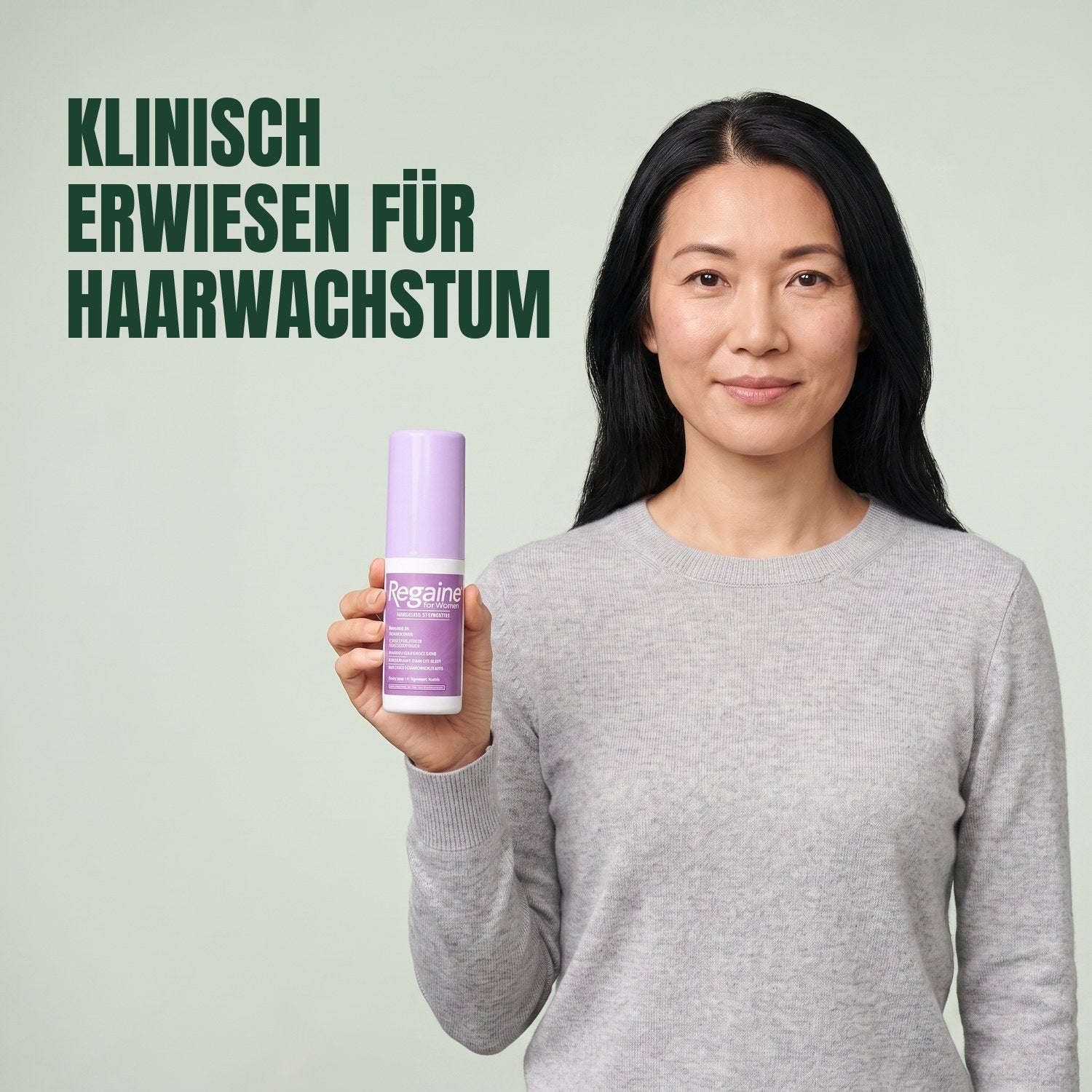 Woman holding the Regaine for Women Minoxidil 2% lotion pack against a green background