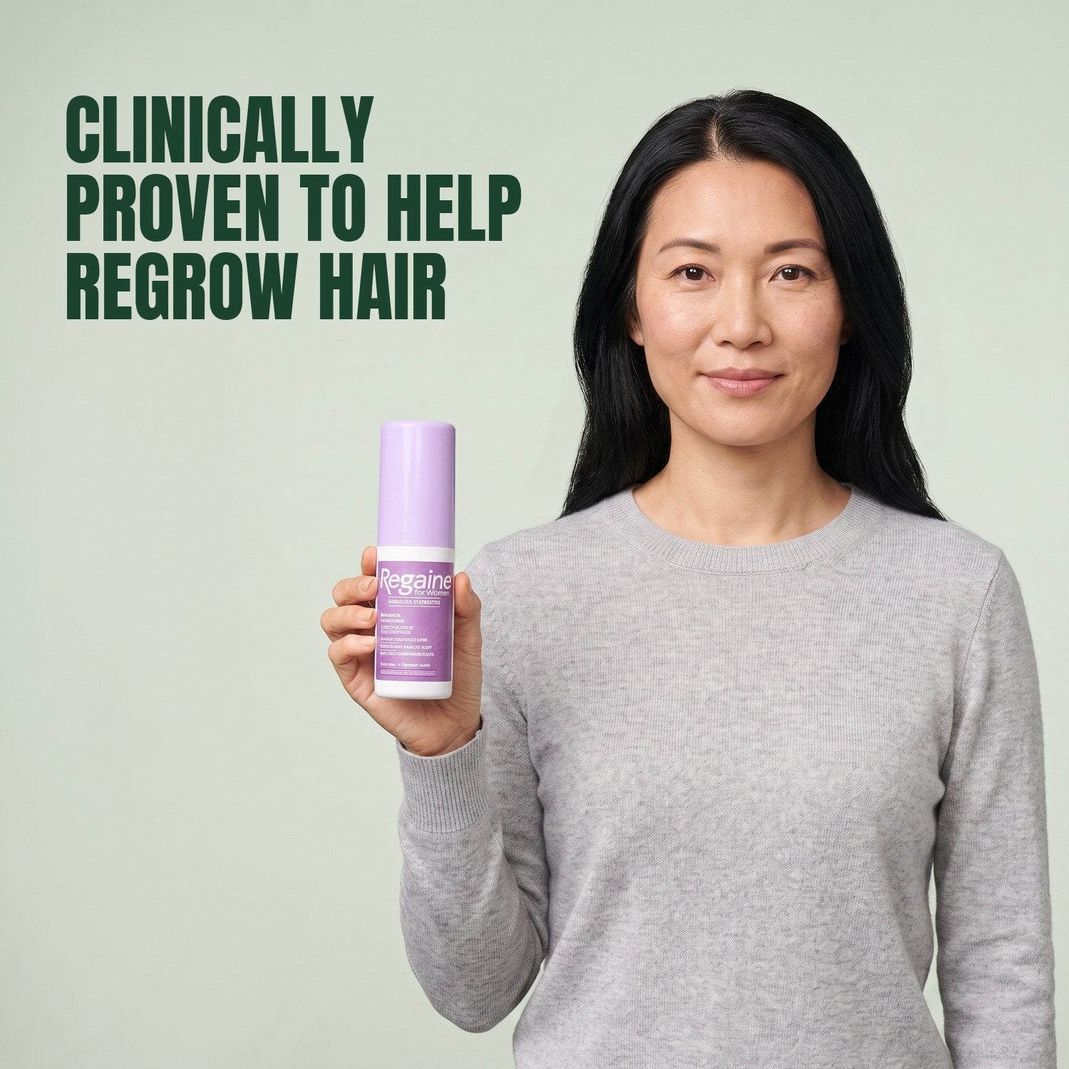 Nő tartja a Regaine for Women Minoxidil 2% oldat csomagját, zöld háttér előtt