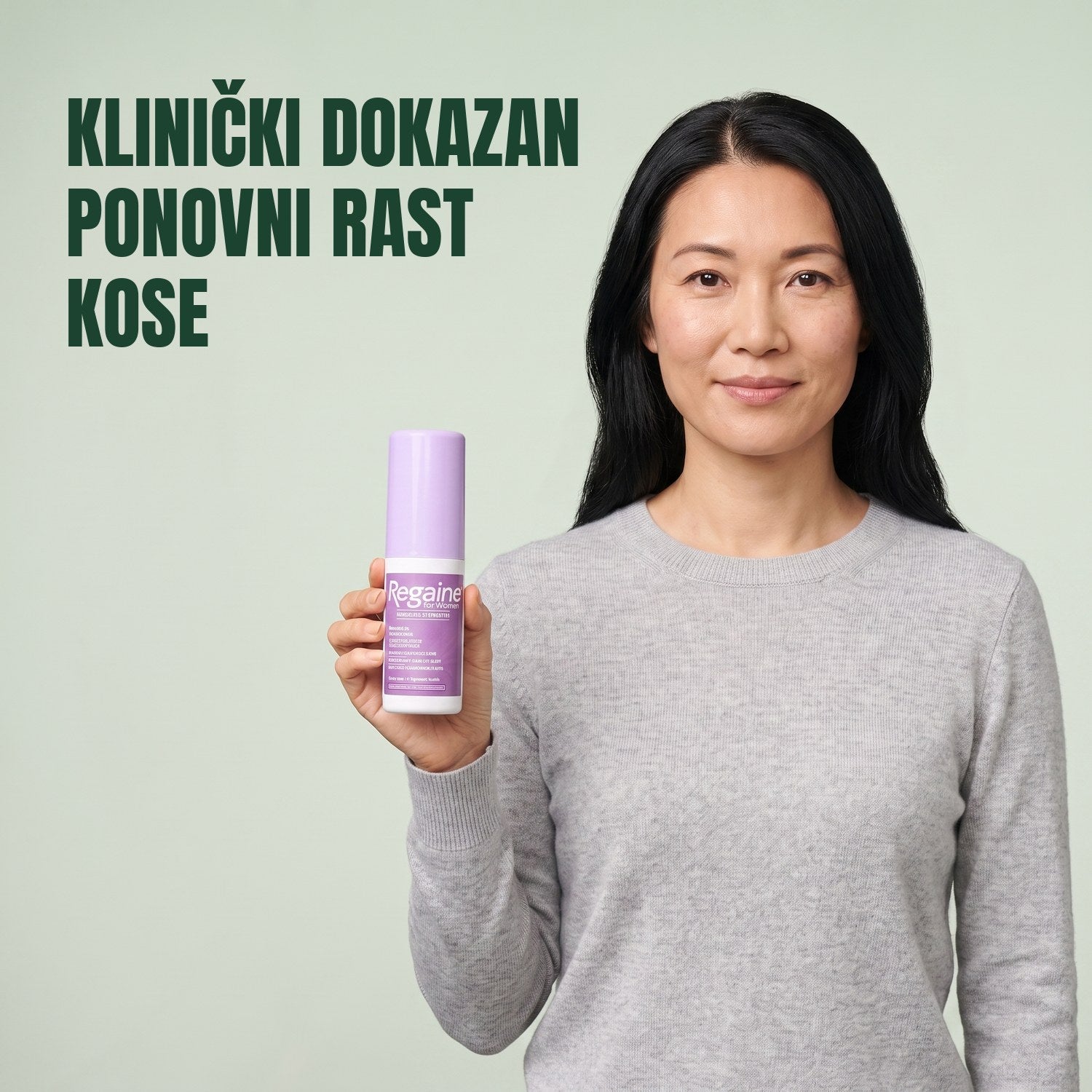 Žena drži pakiranje Regaine for Women Minoxidil 2% losiona na zelenoj pozadini